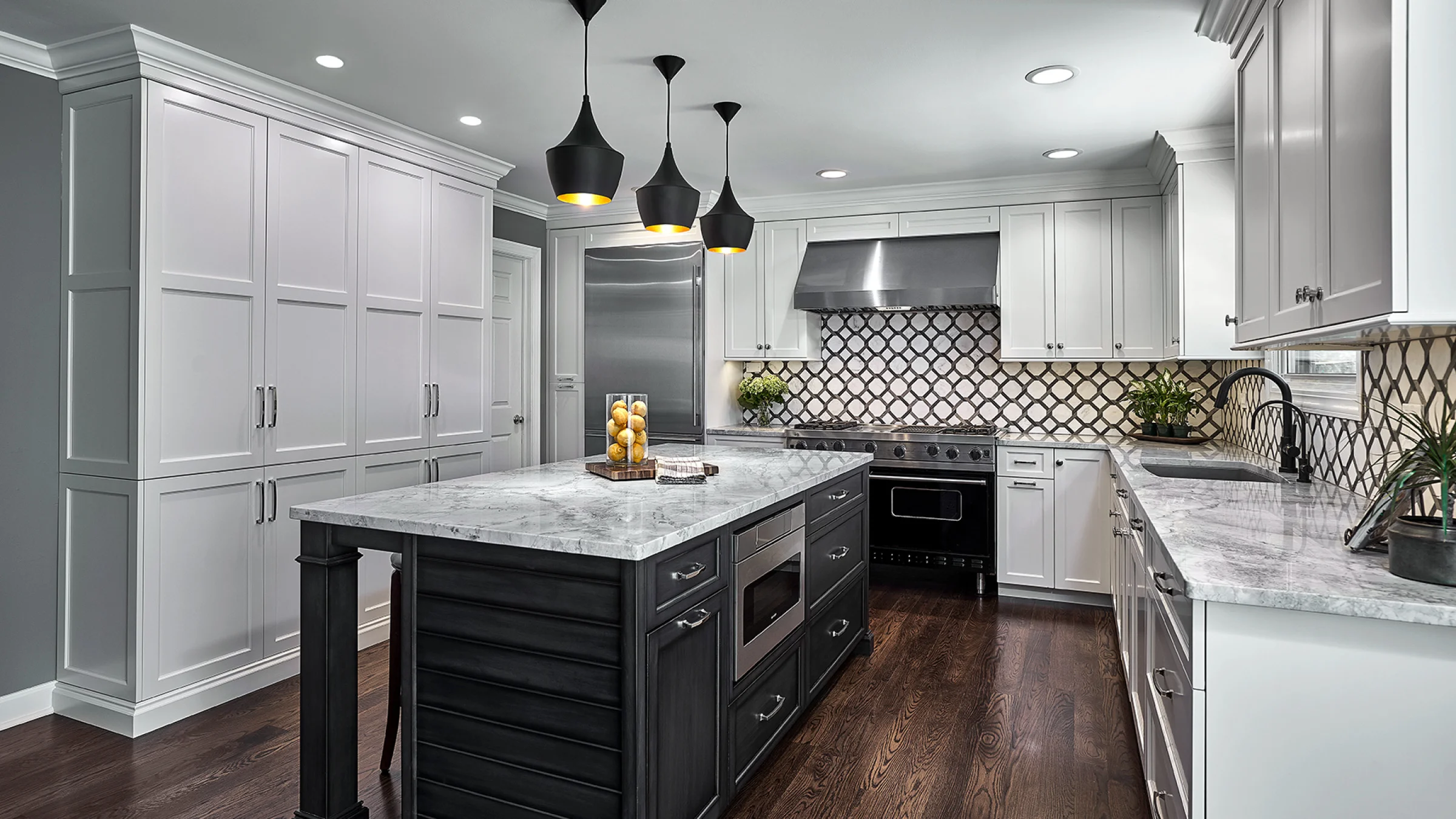 Modern kitchen remodel in Palatine, IL featuring a gray marble island, white cabinets, and dark hardwood floors.