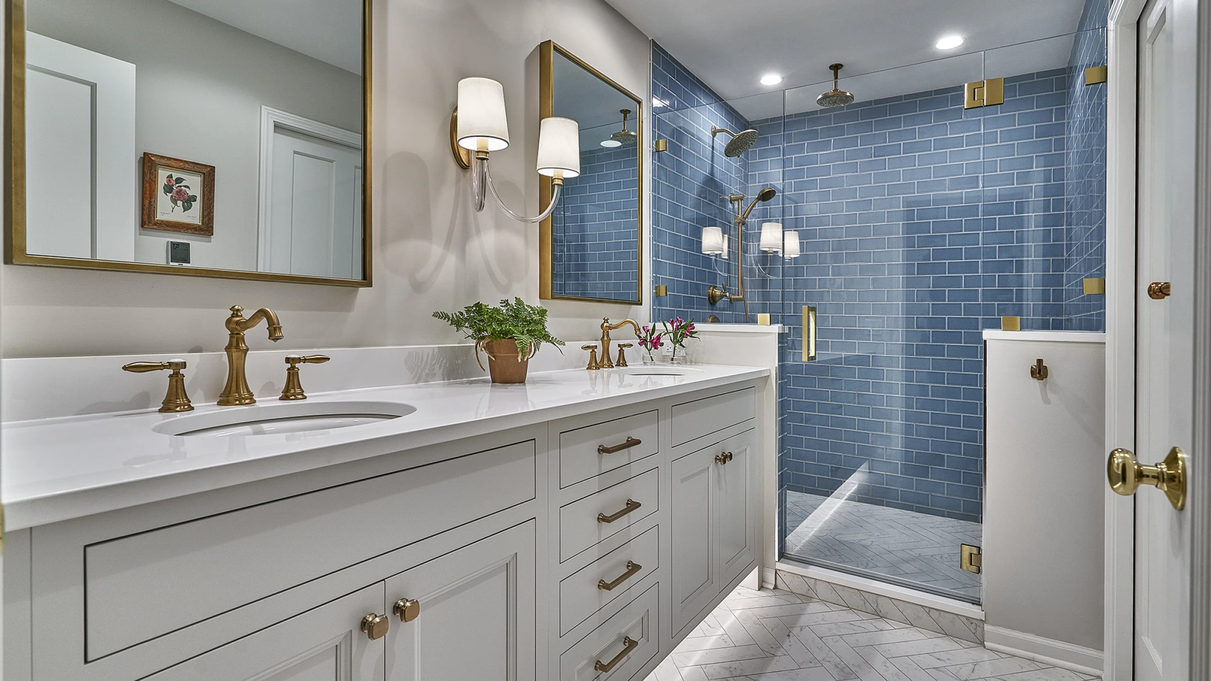 Western Springs bathroom remodel: white vanity, quartz countertop, gold fixtures, blue tile shower, herringbone marble floor.