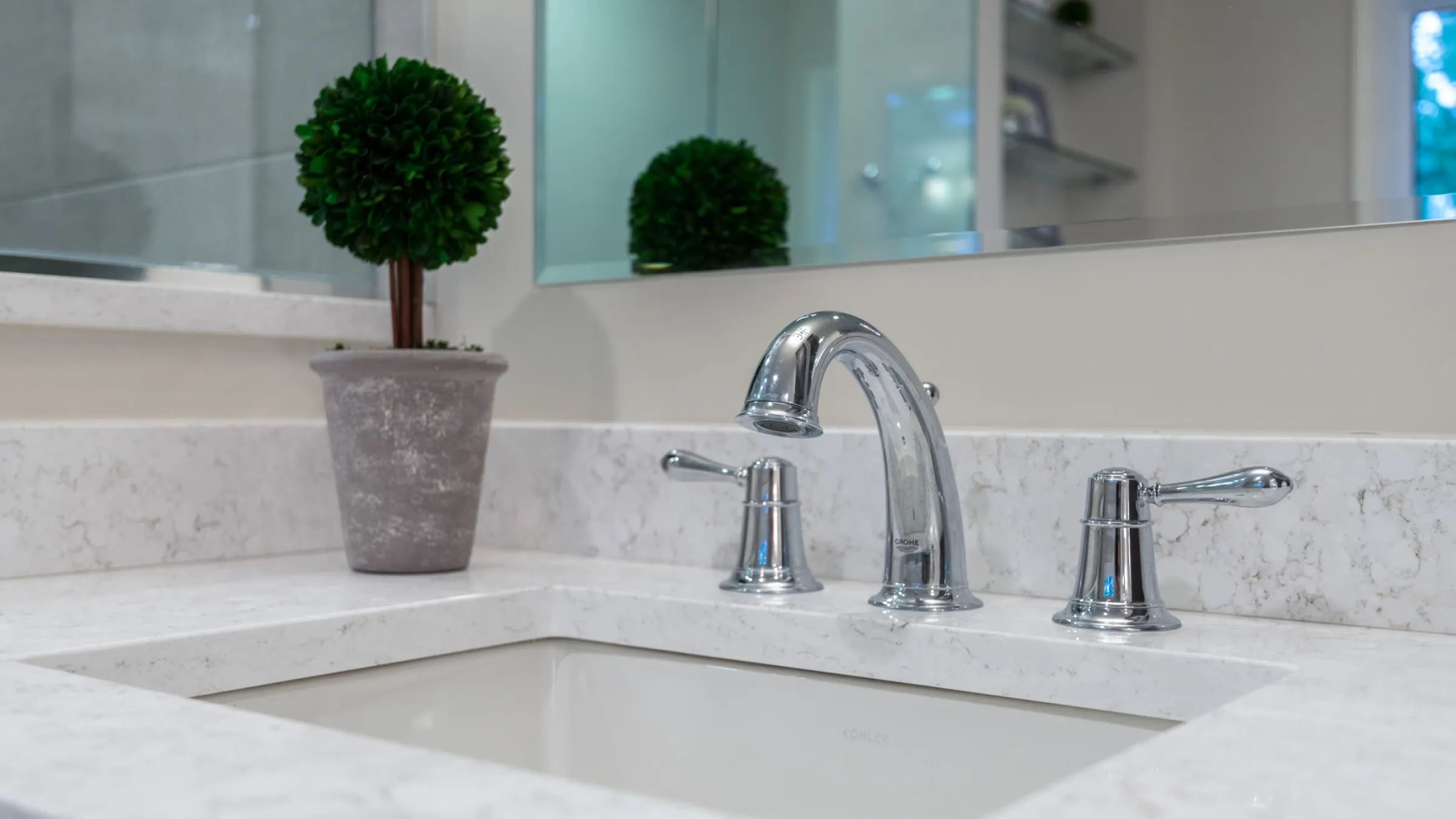 Modern bathroom sink with white quartz countertop, chrome faucet, and decorative plant. Palatine, IL bathroom remodel.