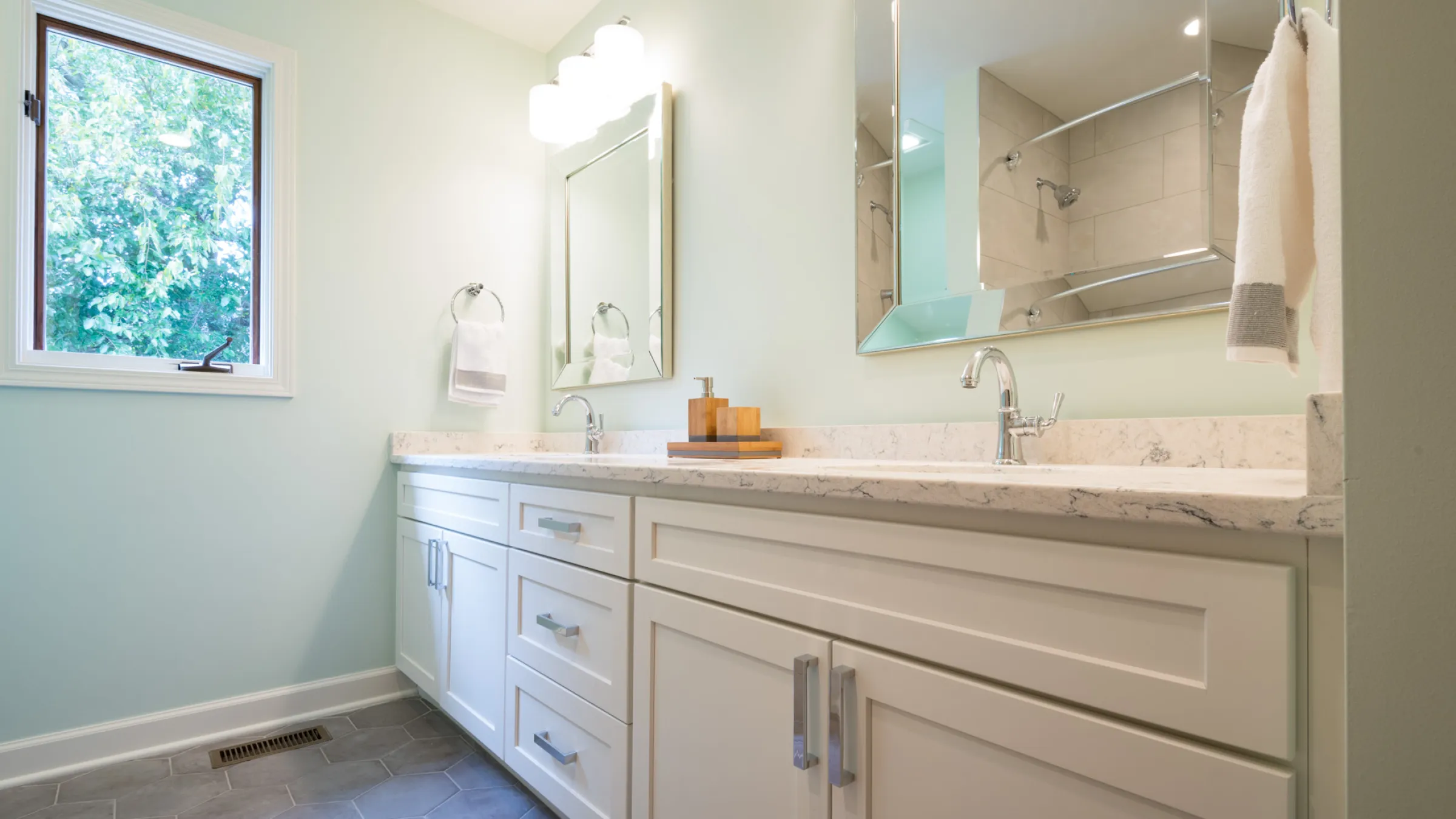 Bright hall bathroom remodel in Palatine, IL with white shaker cabinets, quartz countertop, hexagon tile floor, and natural l