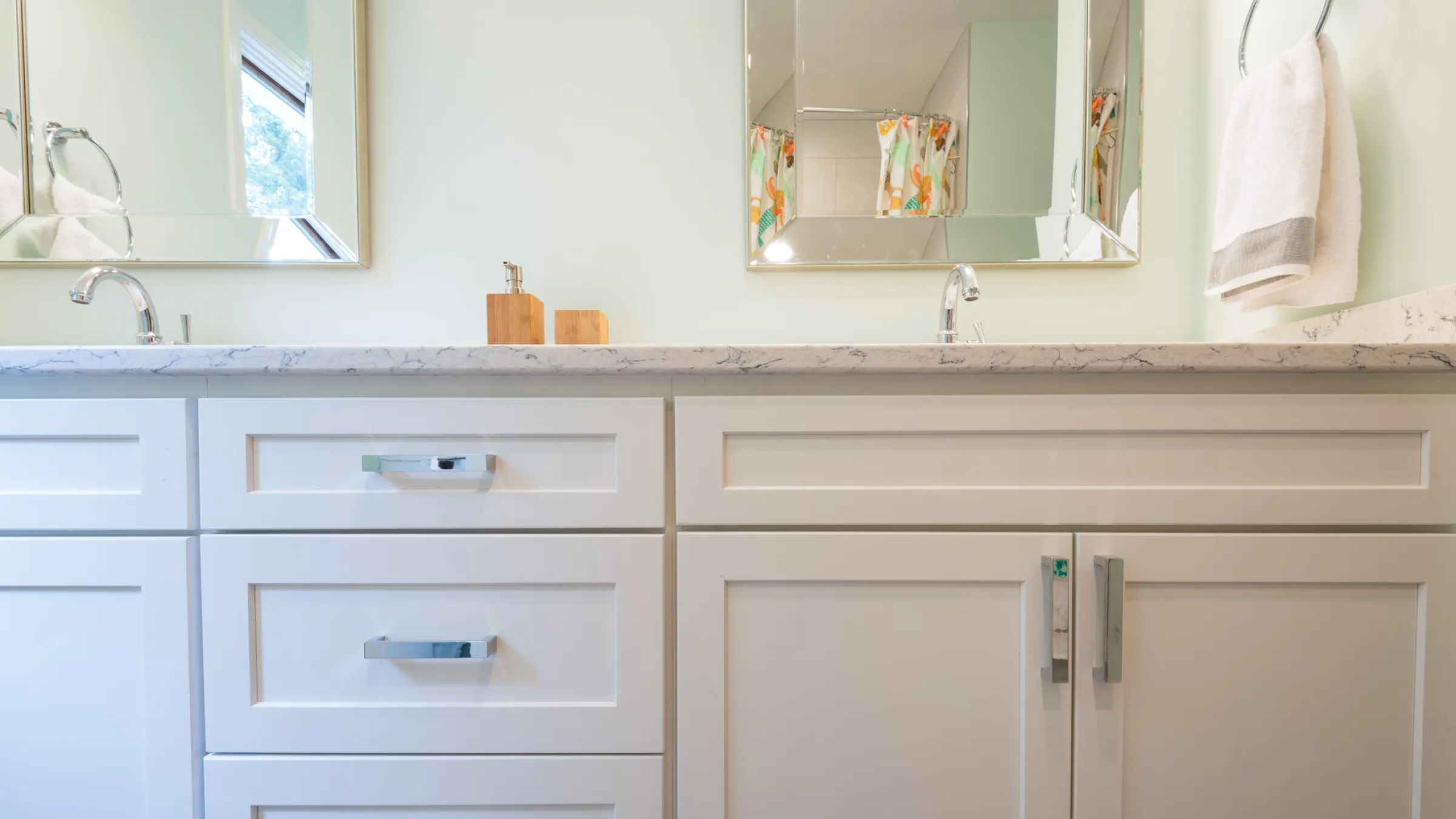 Bathroom remodel with white shaker cabinets, quartz countertop, modern chrome fixtures, and framed mirrors.