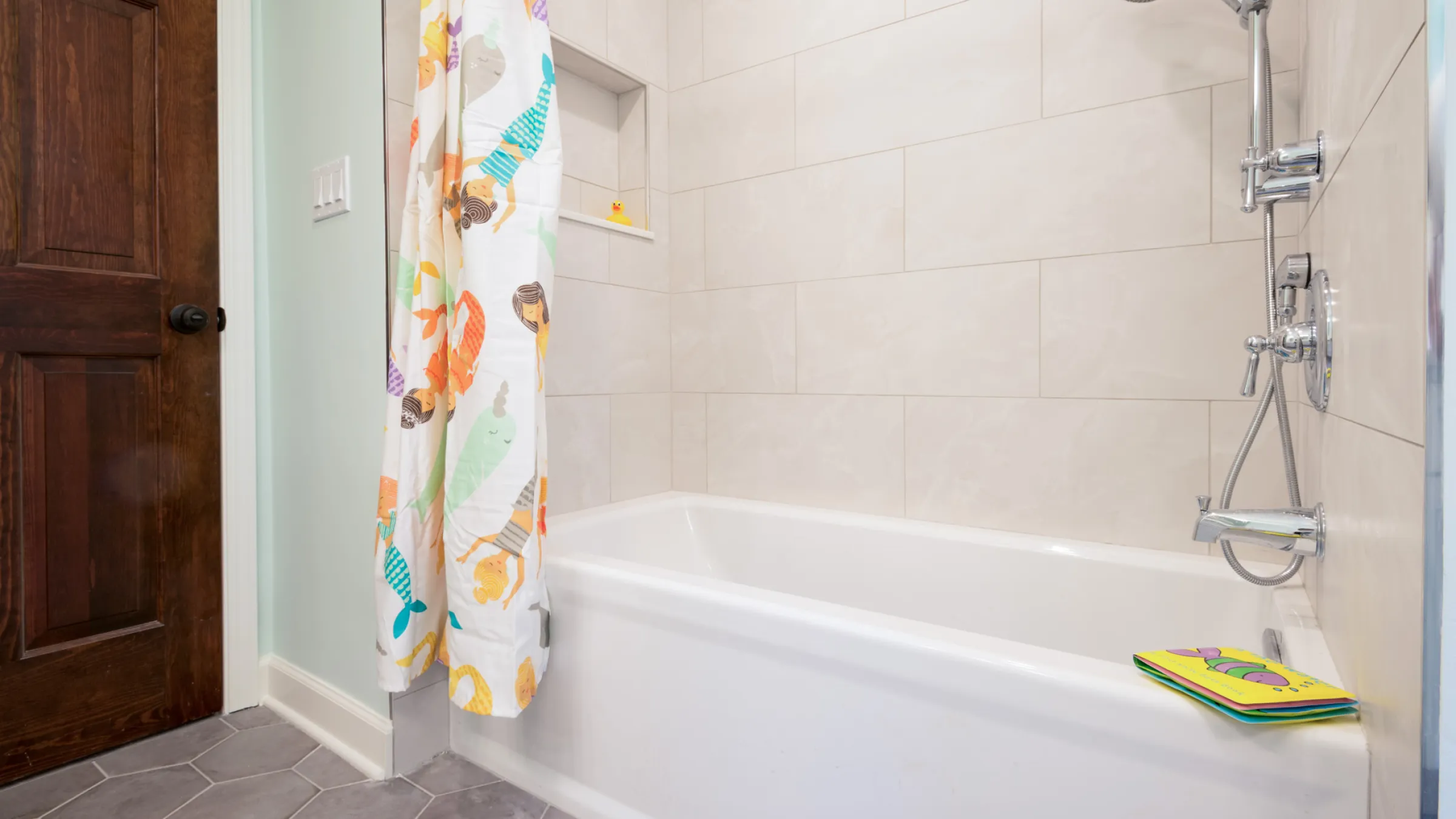 Bathroom remodel in Palatine, IL featuring a white tub, mermaid shower curtain, and modern tile.