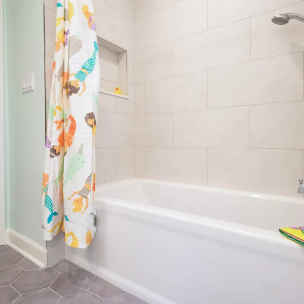 Bathroom remodel in Palatine, IL featuring a white tub, mermaid shower curtain, and modern tile.