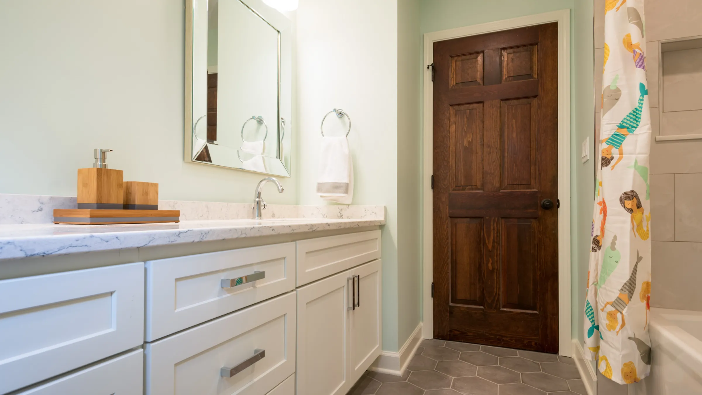 Palatine IL hall bath remodel: white shaker cabinets, quartz countertop, wood door, hexagon tile floor, mermaid shower curtai