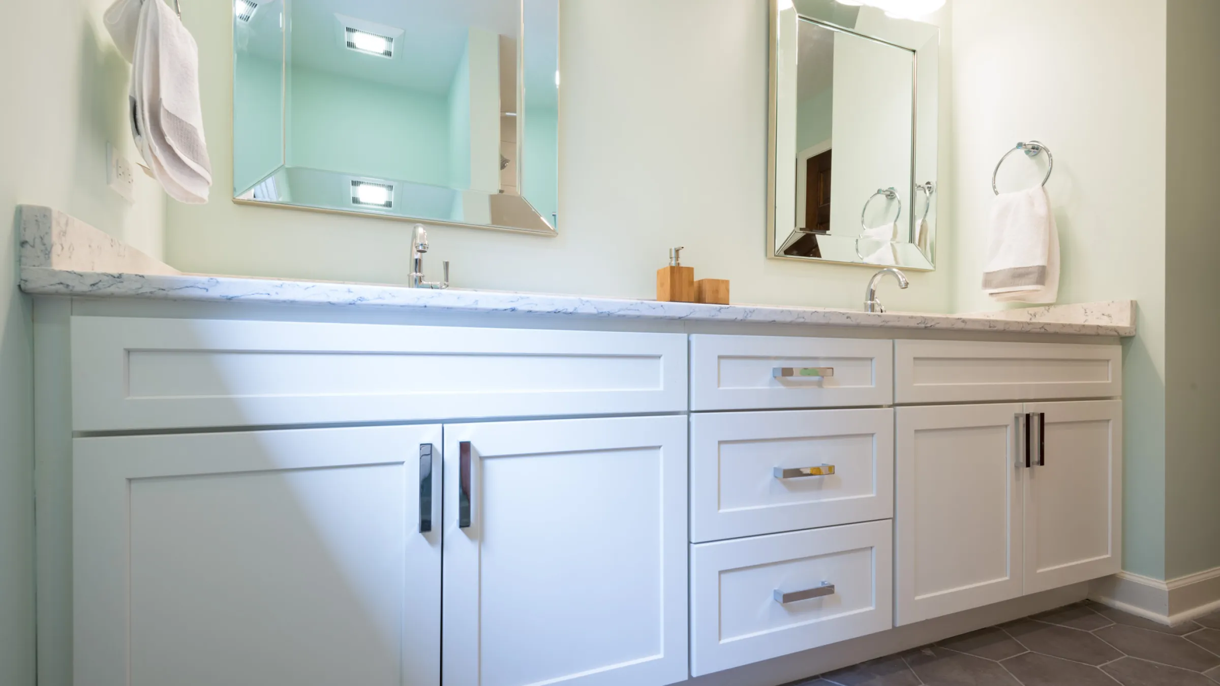 Modern bathroom remodel with white shaker cabinets, marble countertop, chrome fixtures and hexagonal tile floor.