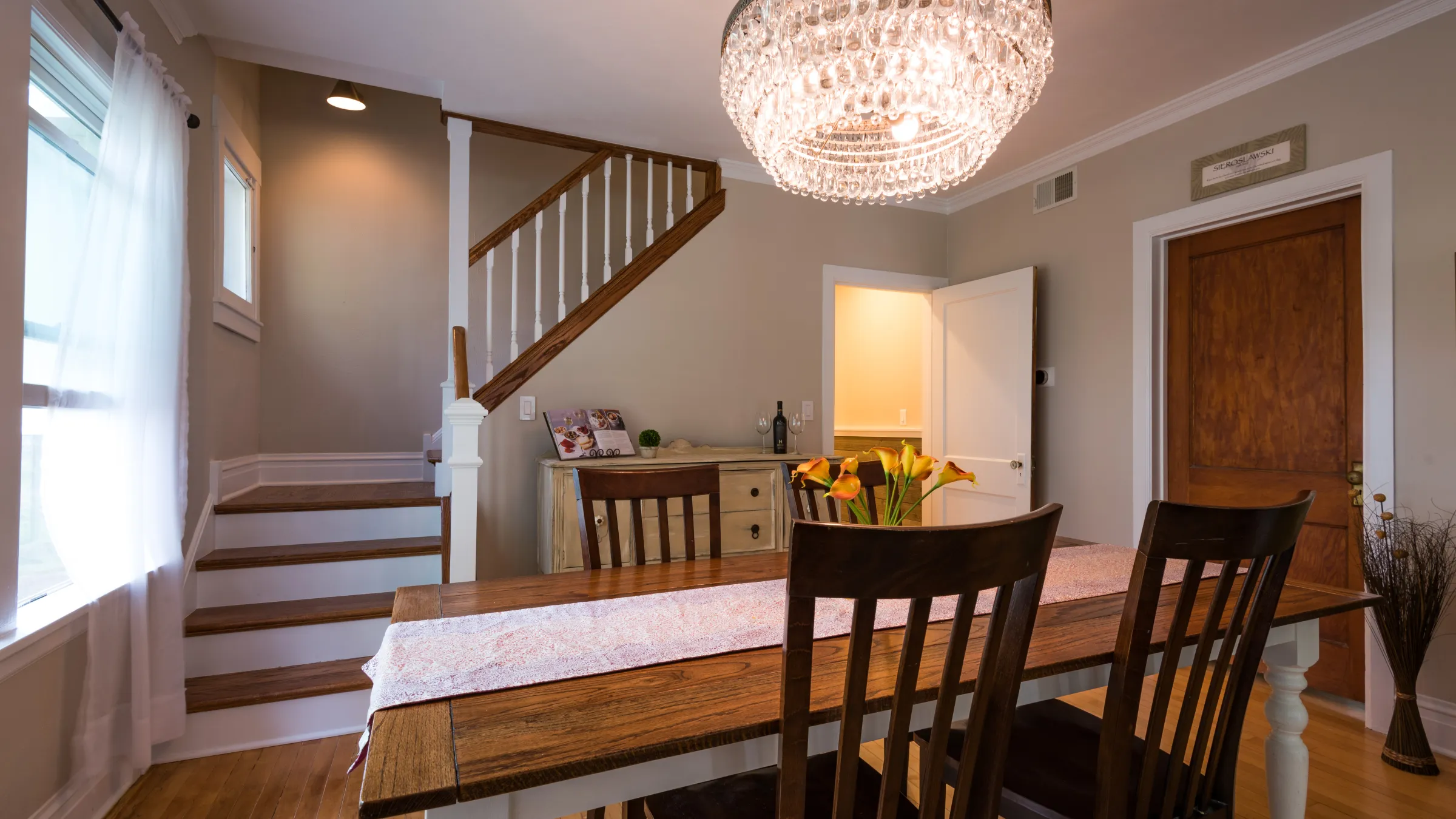 Dining room remodel in Palatine, IL with wood table, chandelier, hardwood floors, and staircase. Historic home renovation.