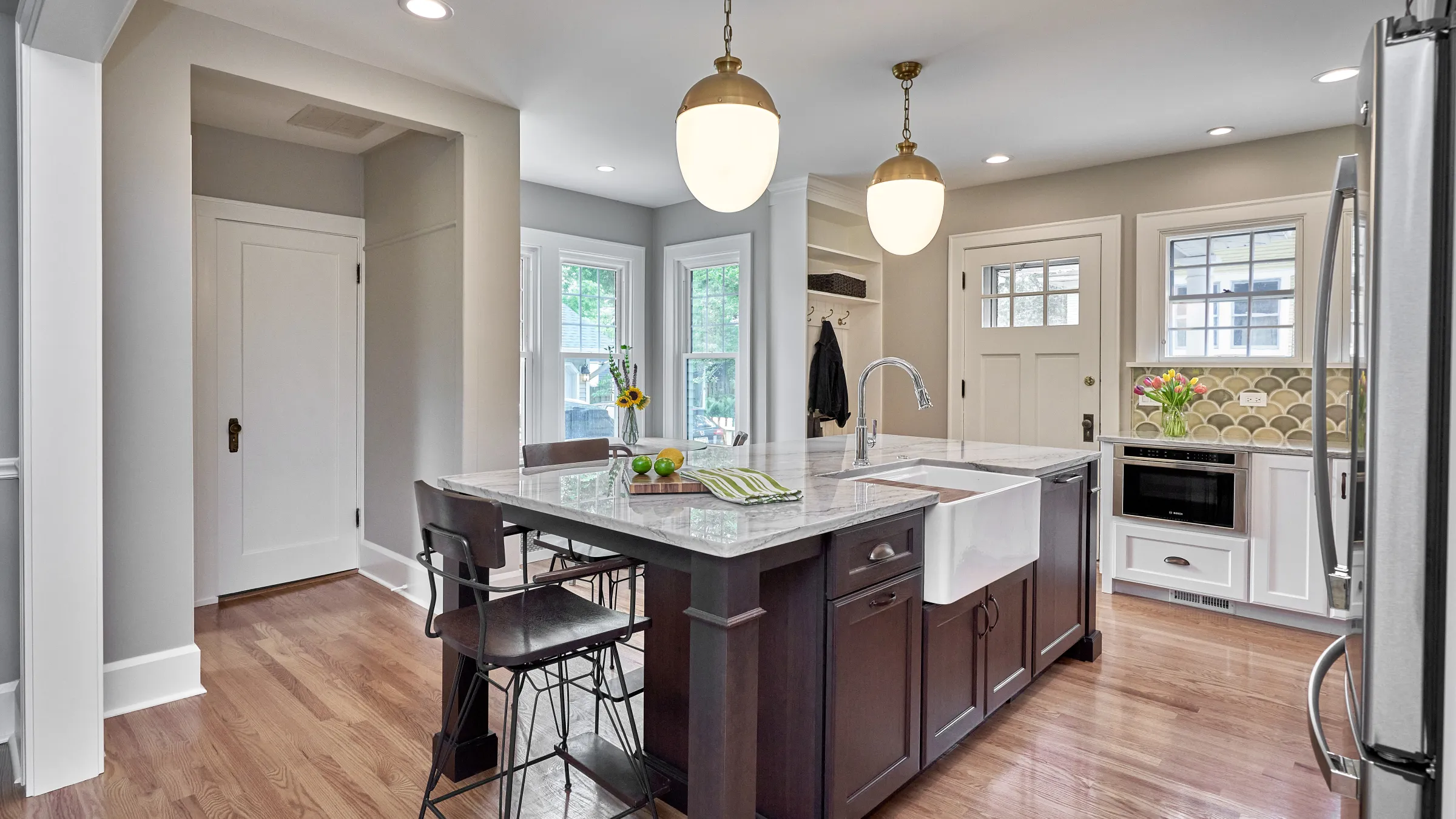 Arlington Heights kitchen remodel: Dark wood island, marble countertop, farmhouse sink, pendant lights, hardwood floors.