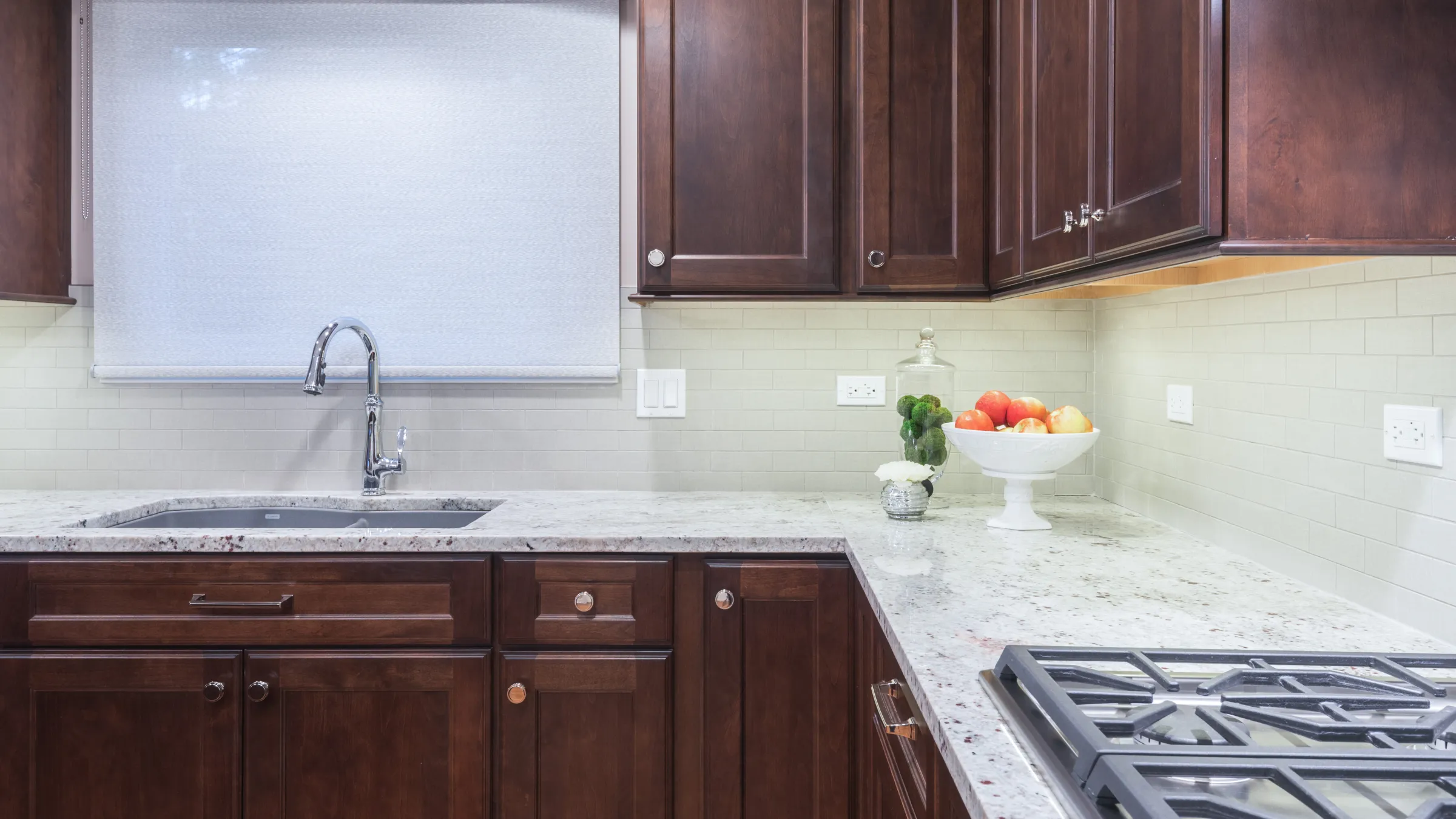 Kitchen remodel featuring dark wood cabinets, granite countertops, subway tile backsplash, and stainless steel sink.