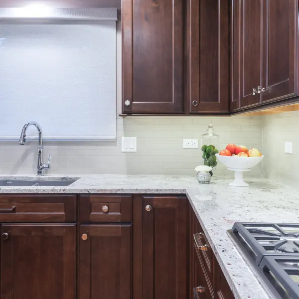 Kitchen remodel featuring dark wood cabinets, granite countertops, subway tile backsplash, and stainless steel sink.