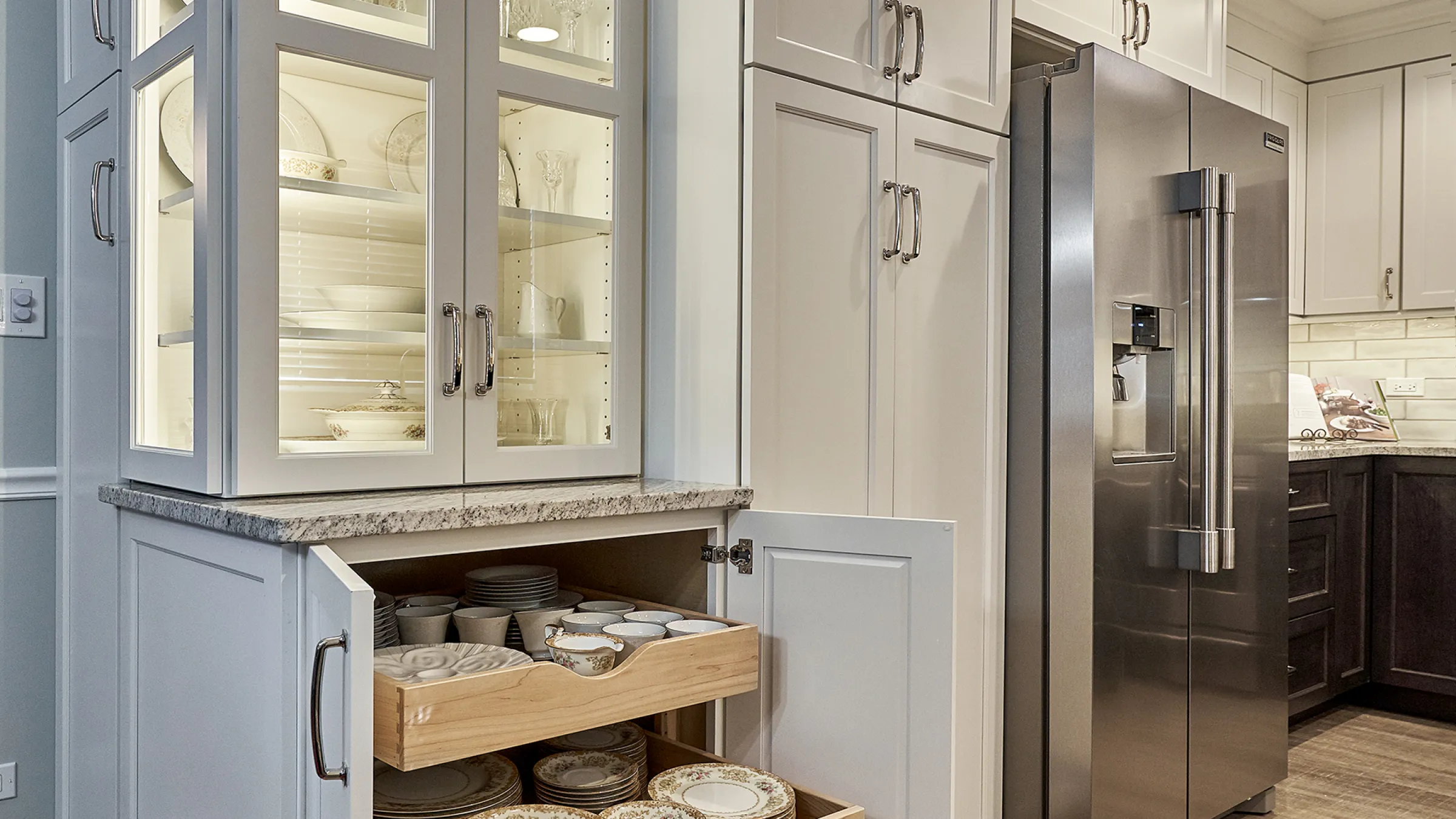Kitchen remodel with white cabinets, granite countertops, stainless steel fridge, and custom dish storage drawers.