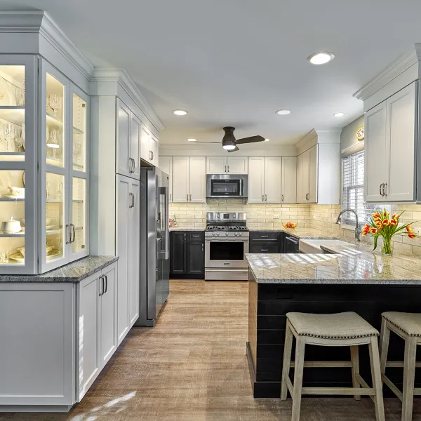 Remodeled kitchen with white cabinets, granite countertops, wood floors, and a breakfast bar with two stools.