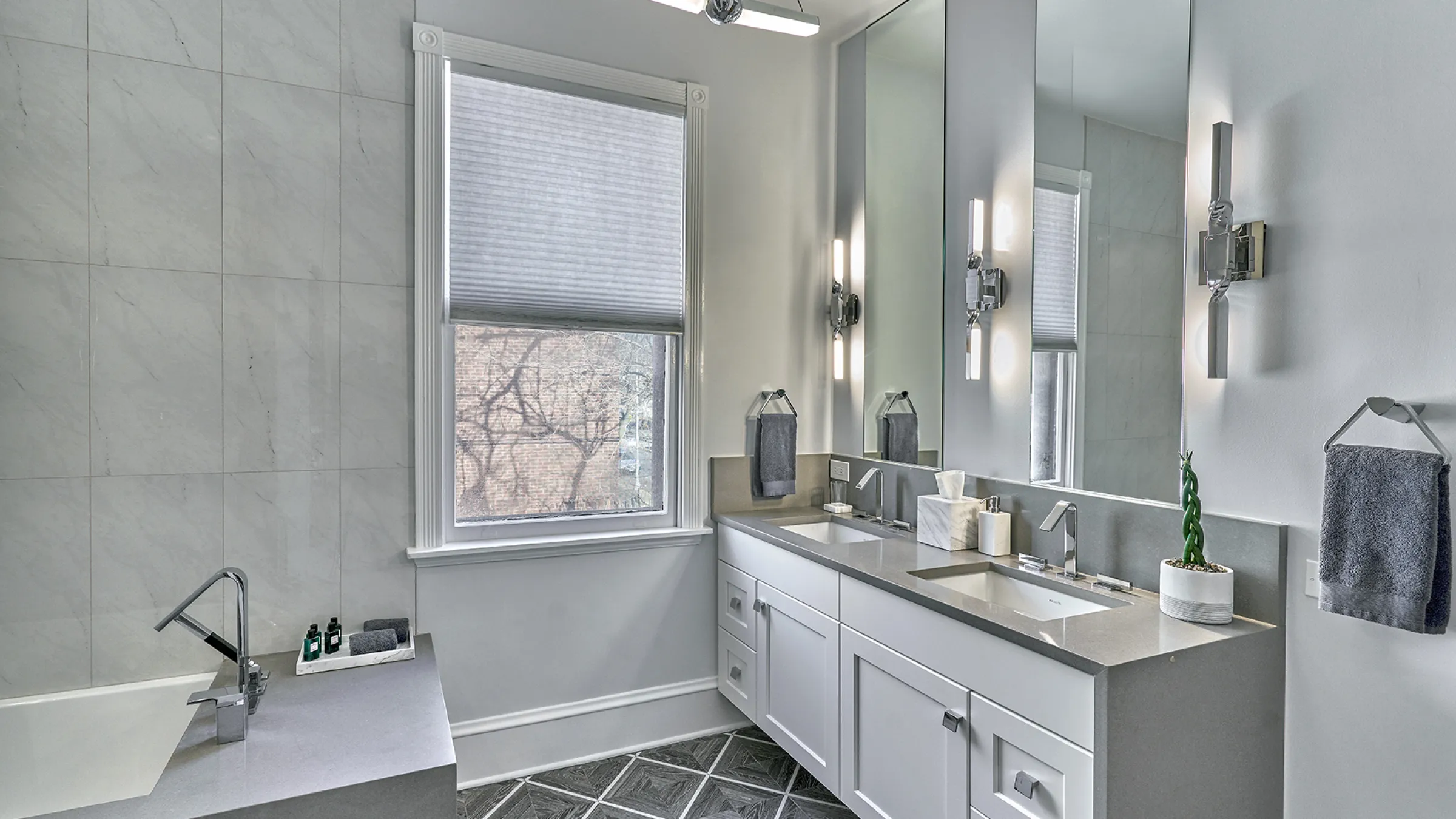 Modern bathroom renovation featuring double vanity, gray countertops, white cabinets, and stylish tile flooring.