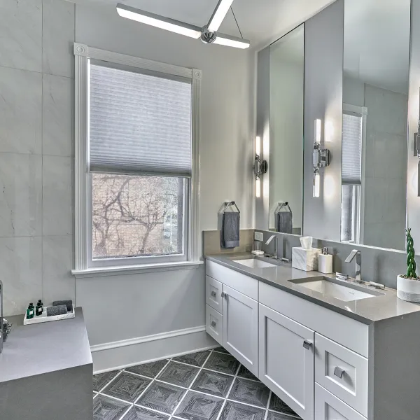 Modern bathroom renovation featuring double vanity, gray countertops, white cabinets, and stylish tile flooring.