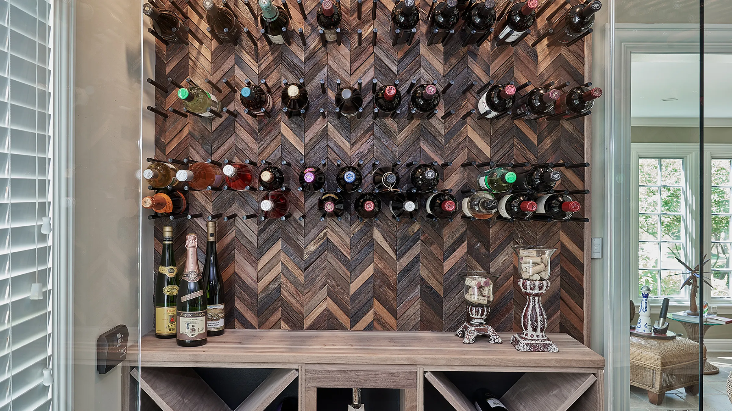 Custom wine cellar in Inverness, IL featuring a herringbone wood wall, wine rack, and display shelf.