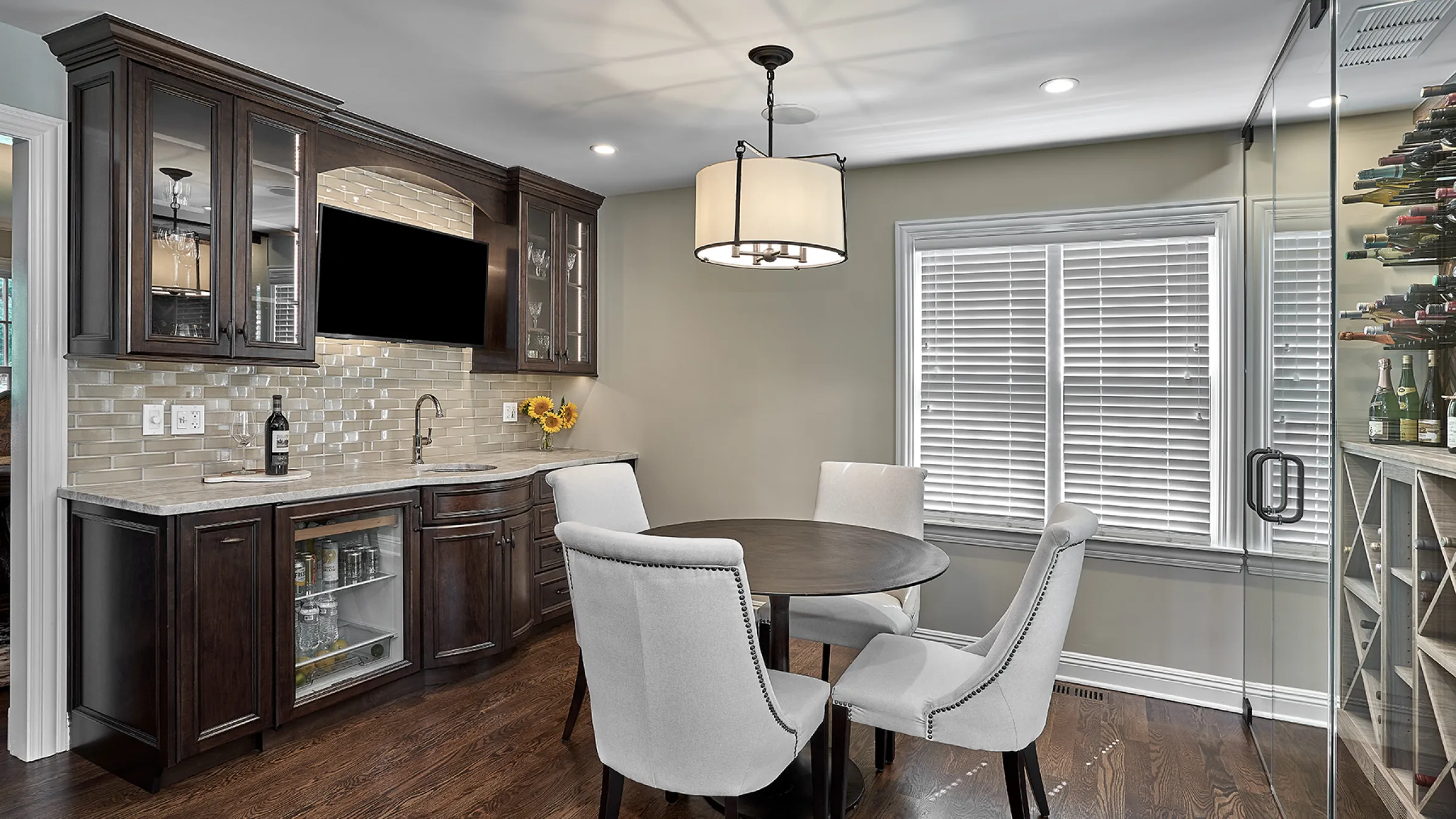 Inverness kitchen remodel with dark wood cabinets, light countertops, wine fridge, and dining table with gray chairs.