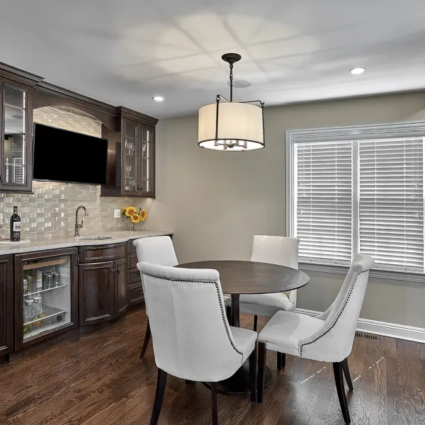 Inverness kitchen remodel with dark wood cabinets, light countertops, wine fridge, and dining table with gray chairs.