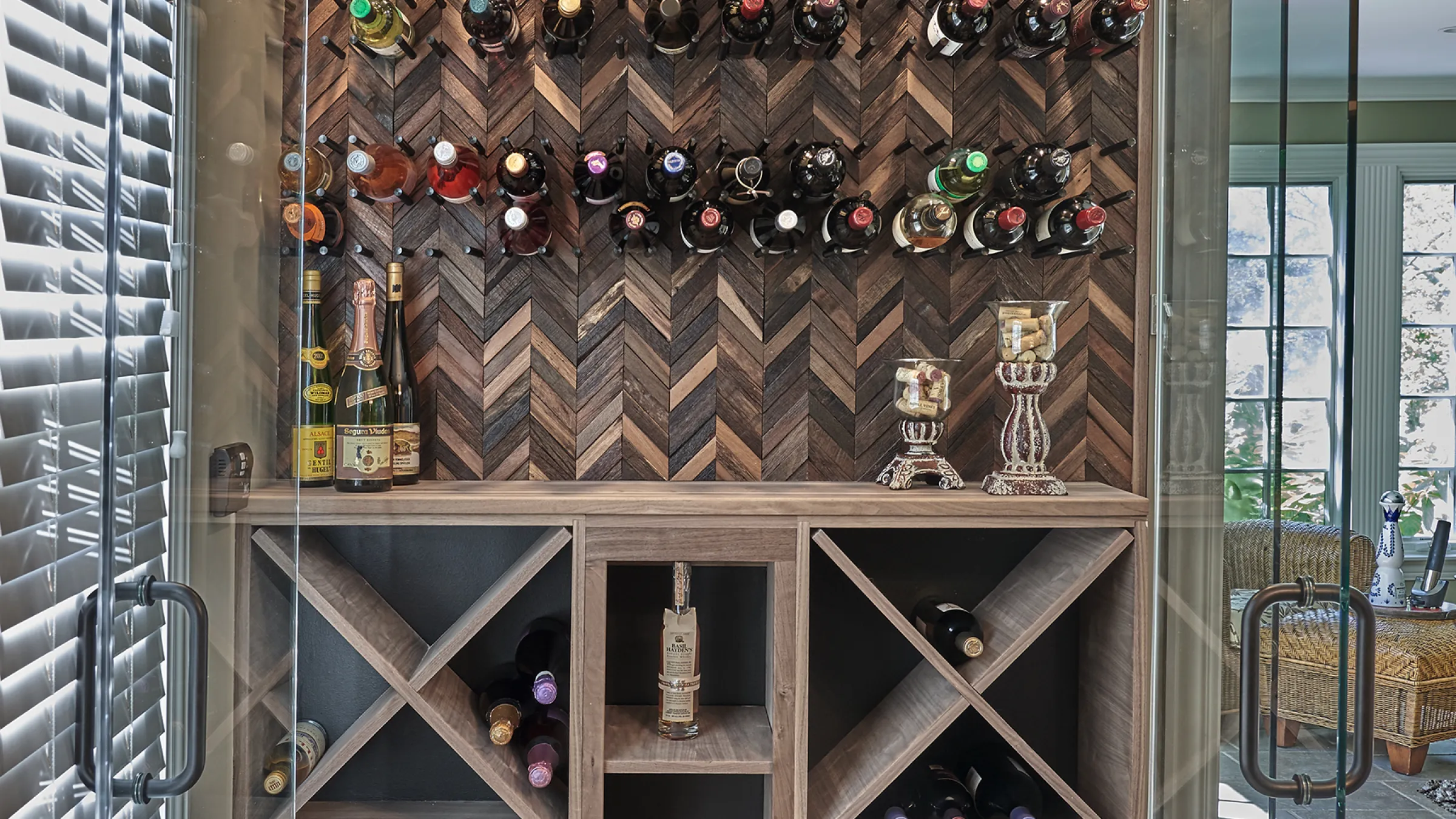 Custom wine cellar with wood herringbone wall, bottle display, and wine storage cabinets.