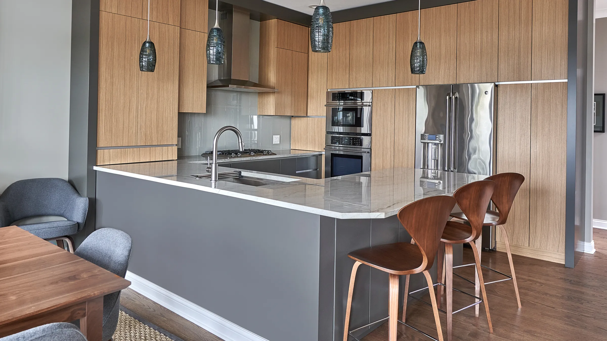Modern kitchen with wood cabinets, gray island, marble countertops, stainless steel appliances, and wood floors in Chicago.