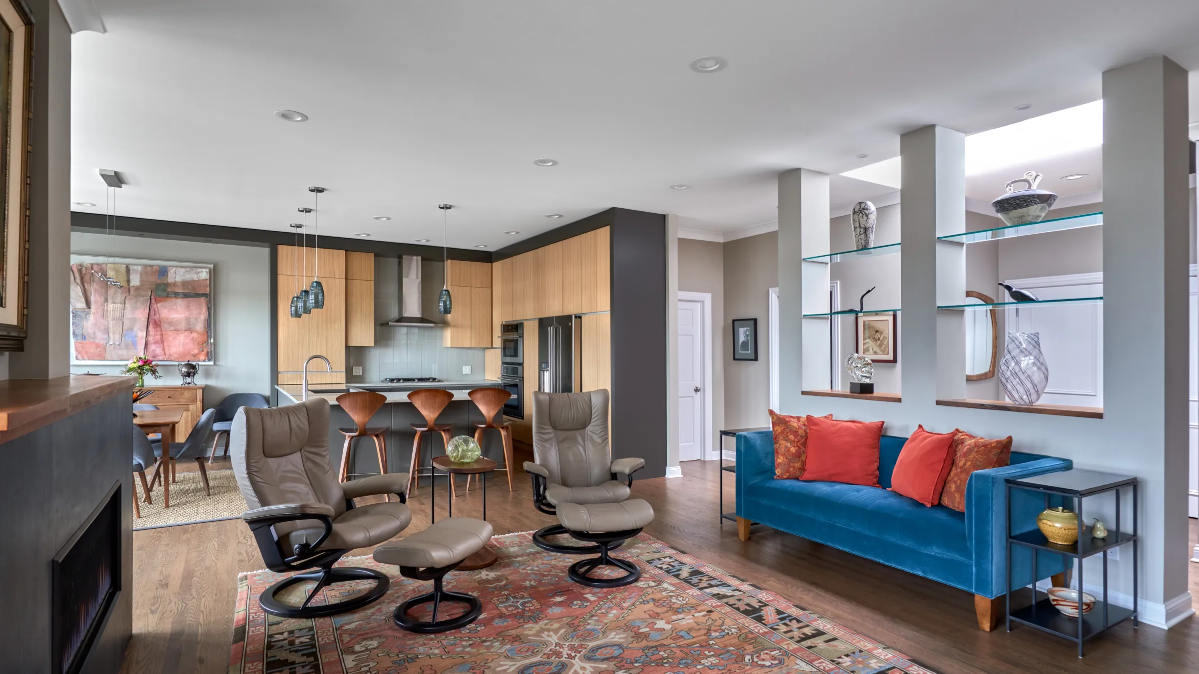 Open concept living room and kitchen remodel with wood cabinets, blue sofa, and hardwood floors in Chicago condo.