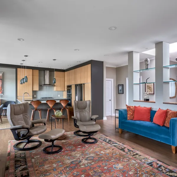 Open concept living room and kitchen remodel with wood cabinets, blue sofa, and hardwood floors in Chicago condo.