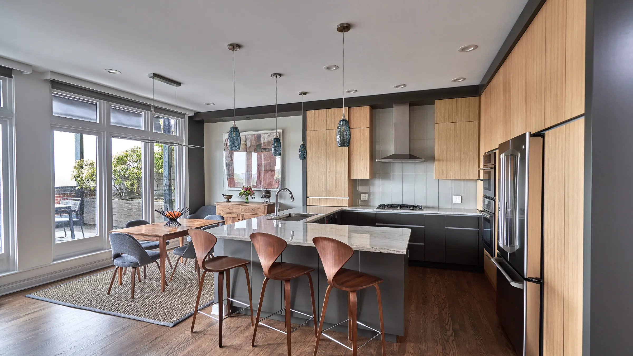 Modern Chicago condo renovation featuring a kitchen with wood cabinets, island with seating, and adjacent dining area.