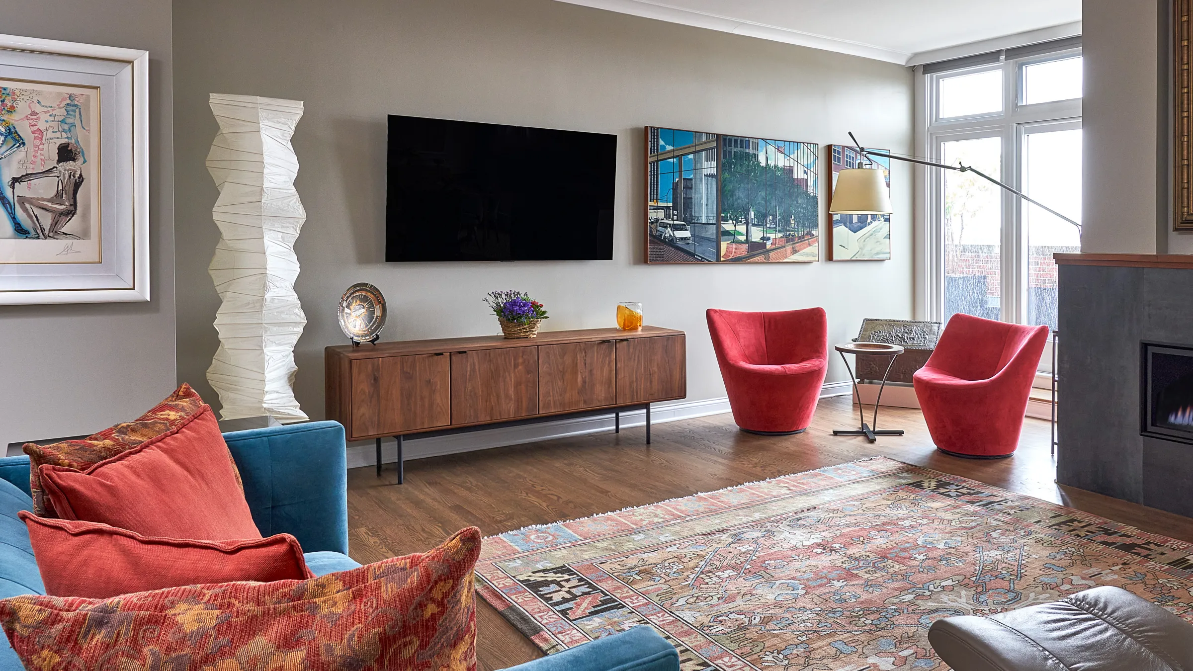 Chicago condo renovation: Living room with wood floors, red chairs, TV, and modern media console.