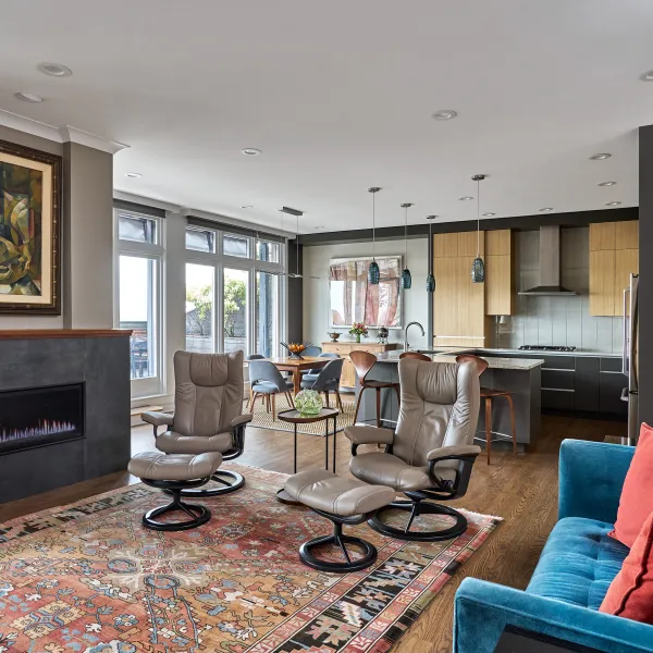Modern condo renovation featuring open-concept living, dining, and kitchen areas in Chicago. Fireplace, wood floors, & lounge