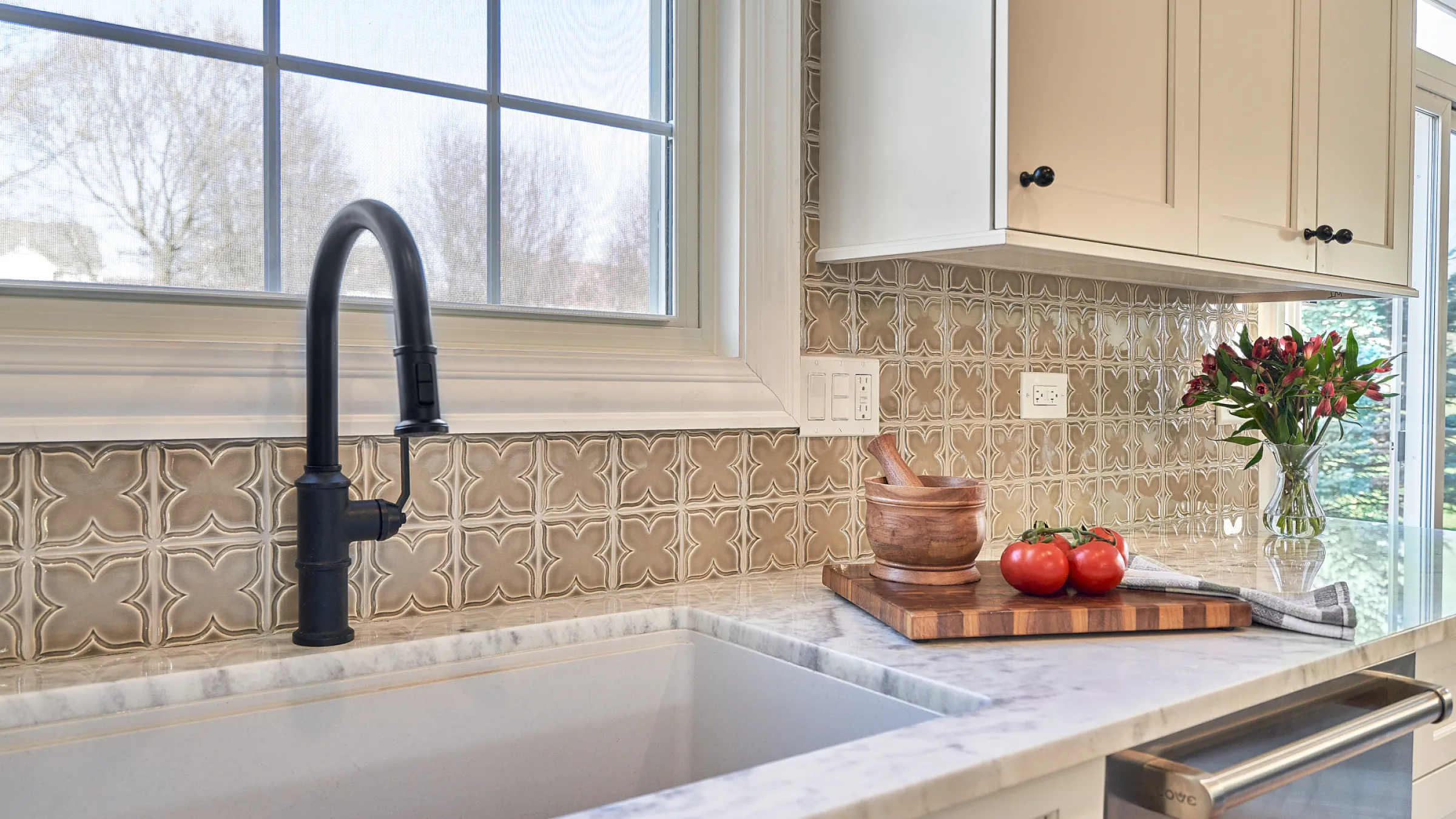Barrington kitchen remodel: farmhouse sink, black faucet, custom backsplash, marble counters, and white cabinets.