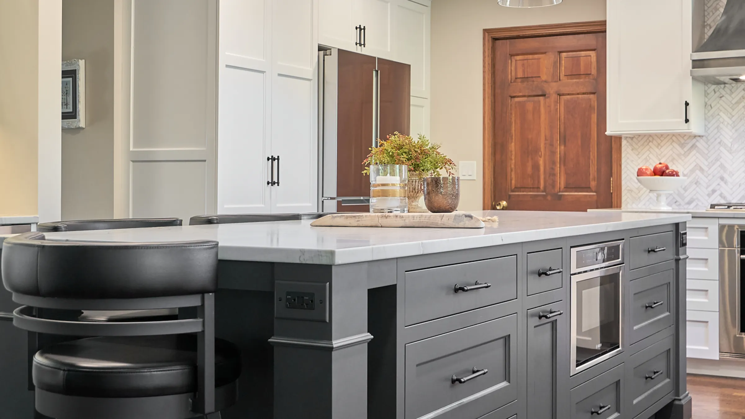 Gray kitchen island with white marble countertop, black bar stools, and stainless steel appliances in Palatine, IL.