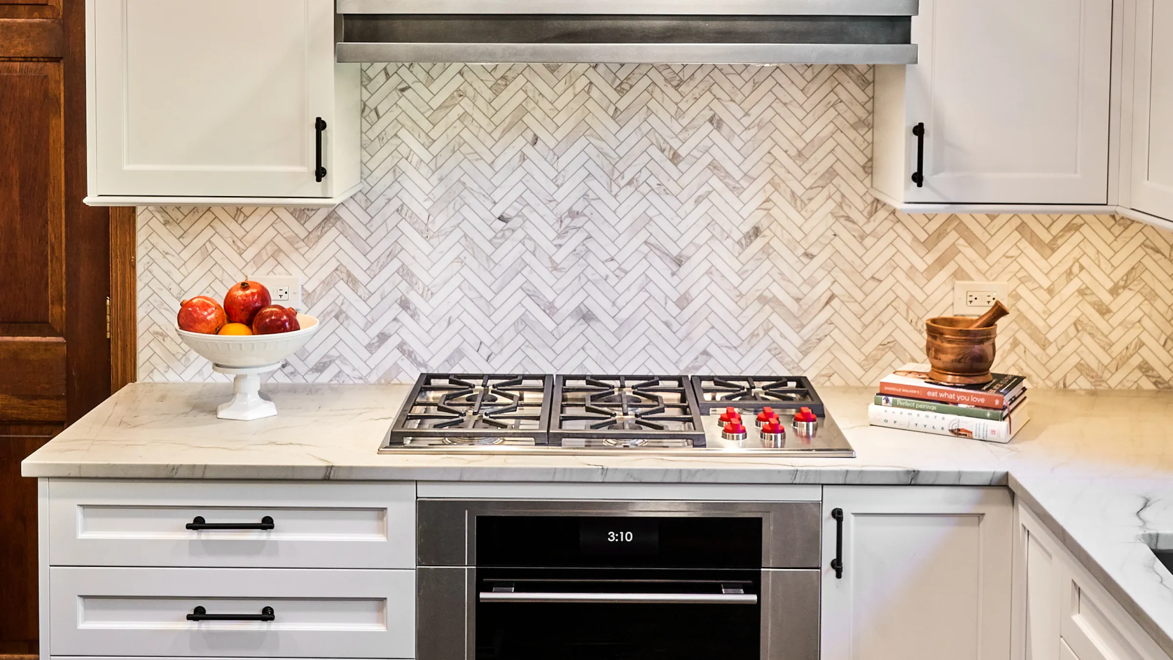 Palatine kitchen remodel featuring white cabinets, herringbone backsplash, and stainless steel appliances.