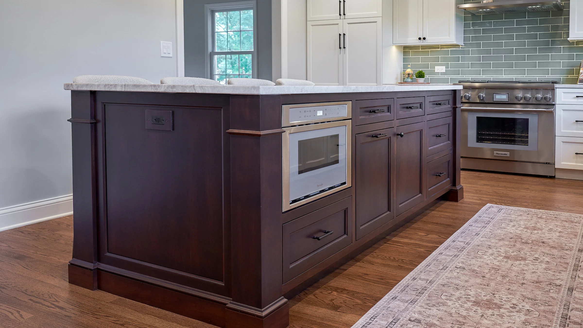 Inverness kitchen island with dark wood cabinets, marble countertop, built-in microwave, and hardwood floors.
