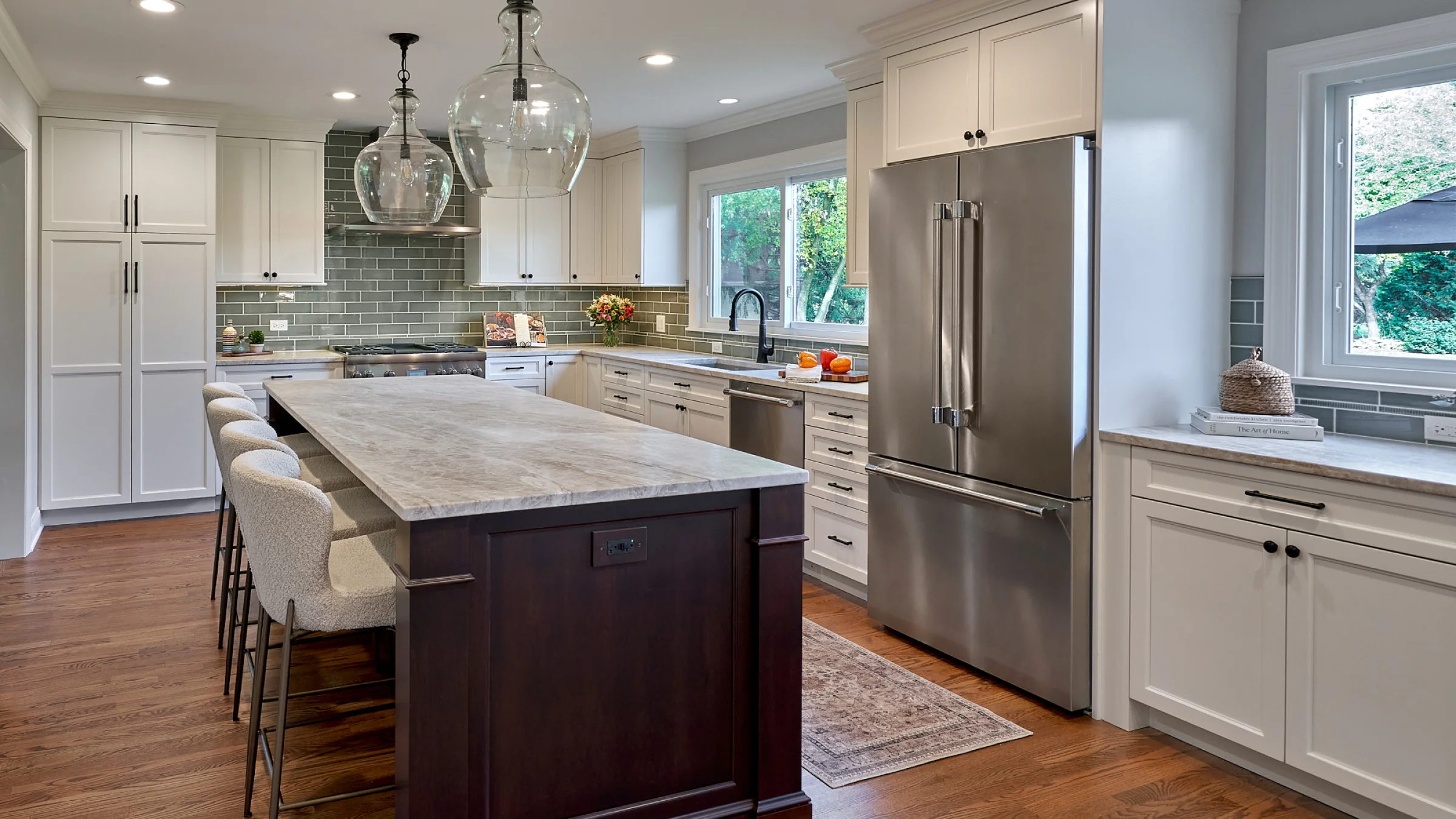 Inverness kitchen remodel featuring white cabinets, marble countertops, wood floors, and a dark wood island with seating.