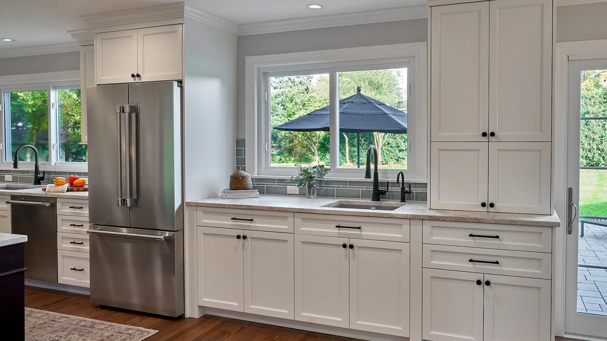 Inverness kitchen remodel: White shaker cabinets, stainless steel fridge, dark hardware, hardwood floors, gray tile backsplas