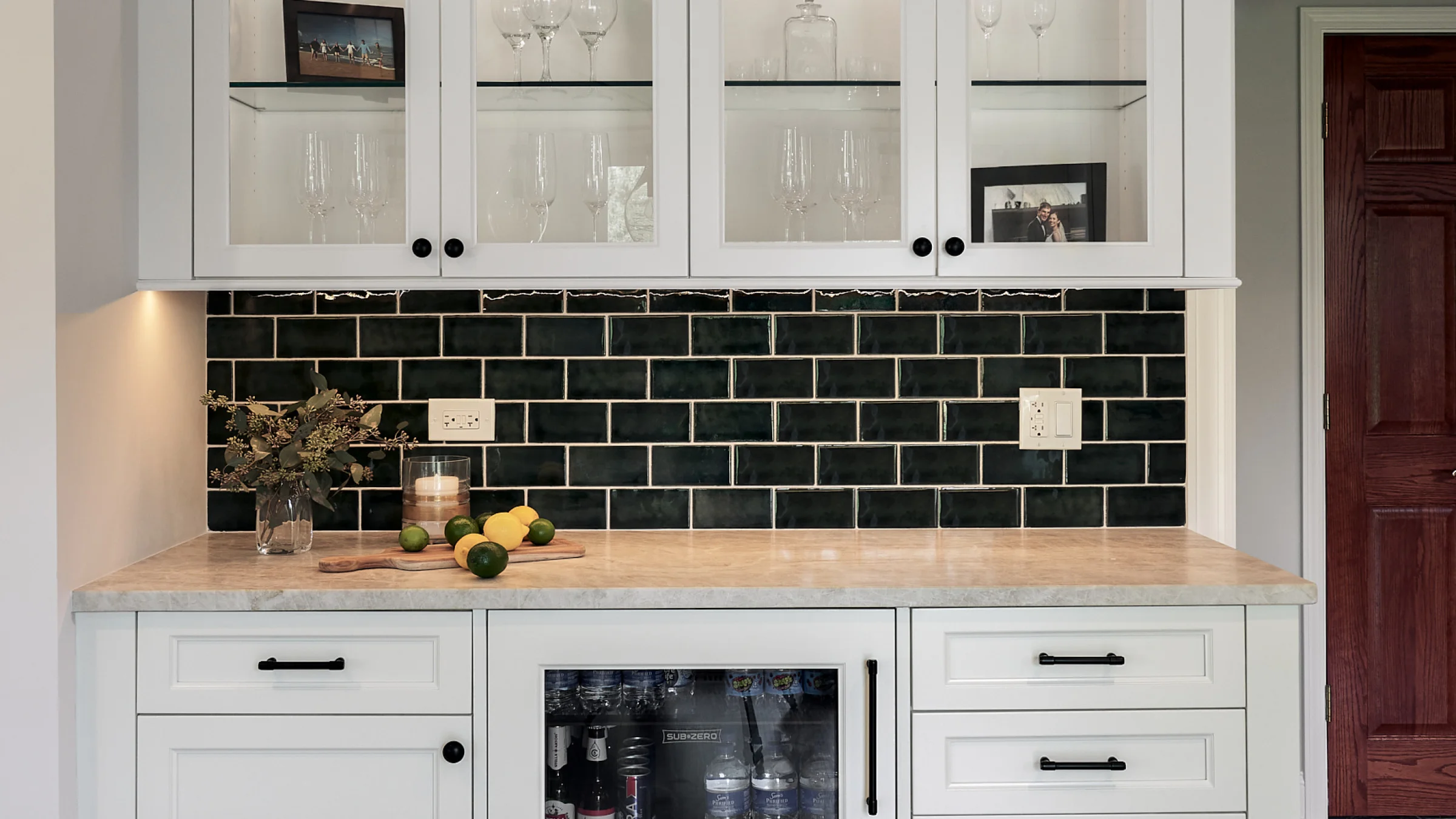Inverness home remodel: White cabinets, dark tile backsplash, marble countertop, and beverage fridge. Chic wet bar design.