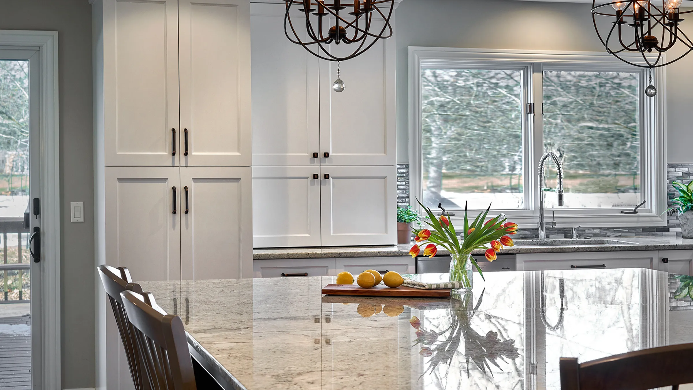 Bright kitchen remodel featuring white cabinets, granite countertops, and a modern chandelier. Long Grove, IL.