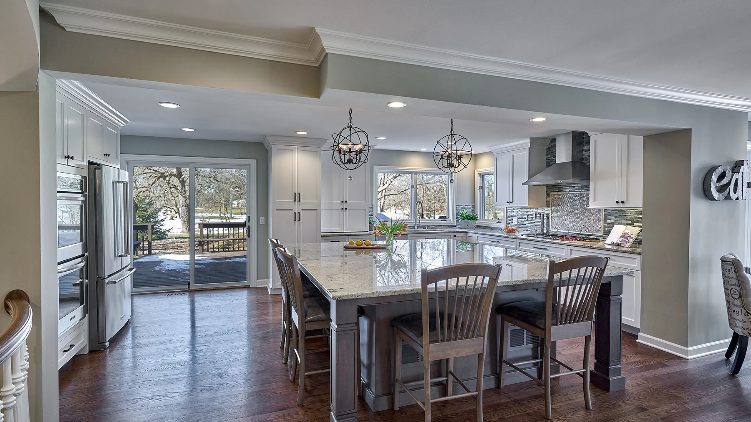 Remodeled kitchen with island, granite countertops, hardwood floors, white cabinets, and stainless steel appliances.