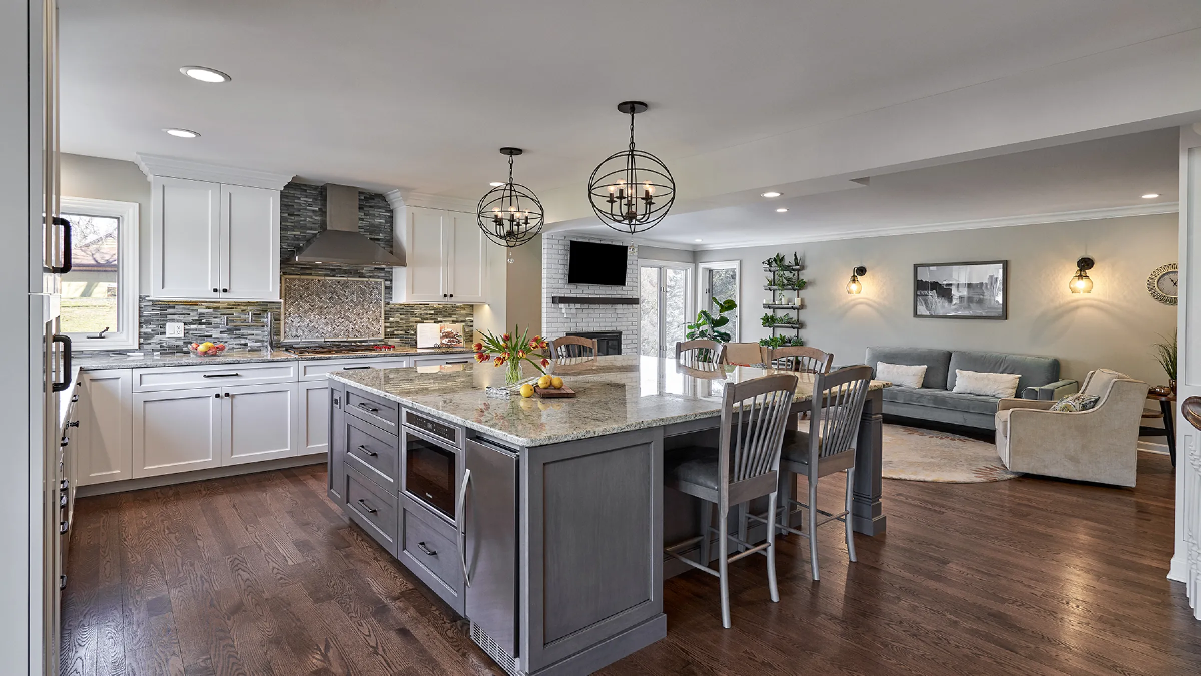 Remodeled kitchen and living room in Long Grove, IL. Features a kitchen island, white cabinets, and hardwood floors.