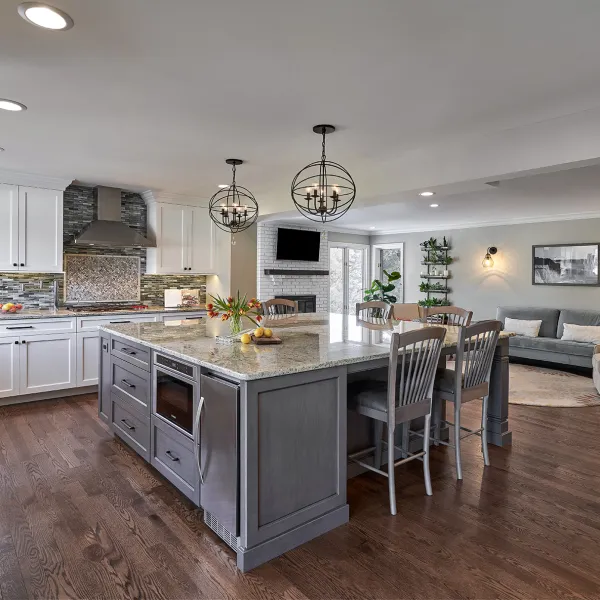 Remodeled kitchen and living room in Long Grove, IL. Features a kitchen island, white cabinets, and hardwood floors.