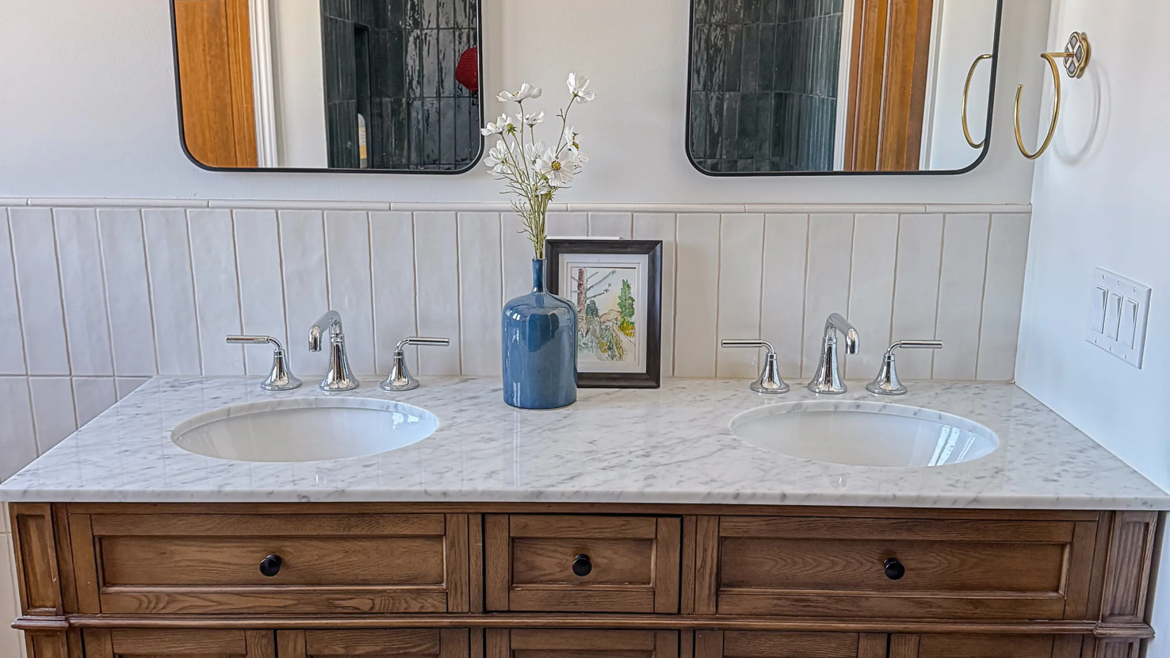 Bathroom remodel with double vanity, marble countertop, wood cabinets, and modern fixtures.