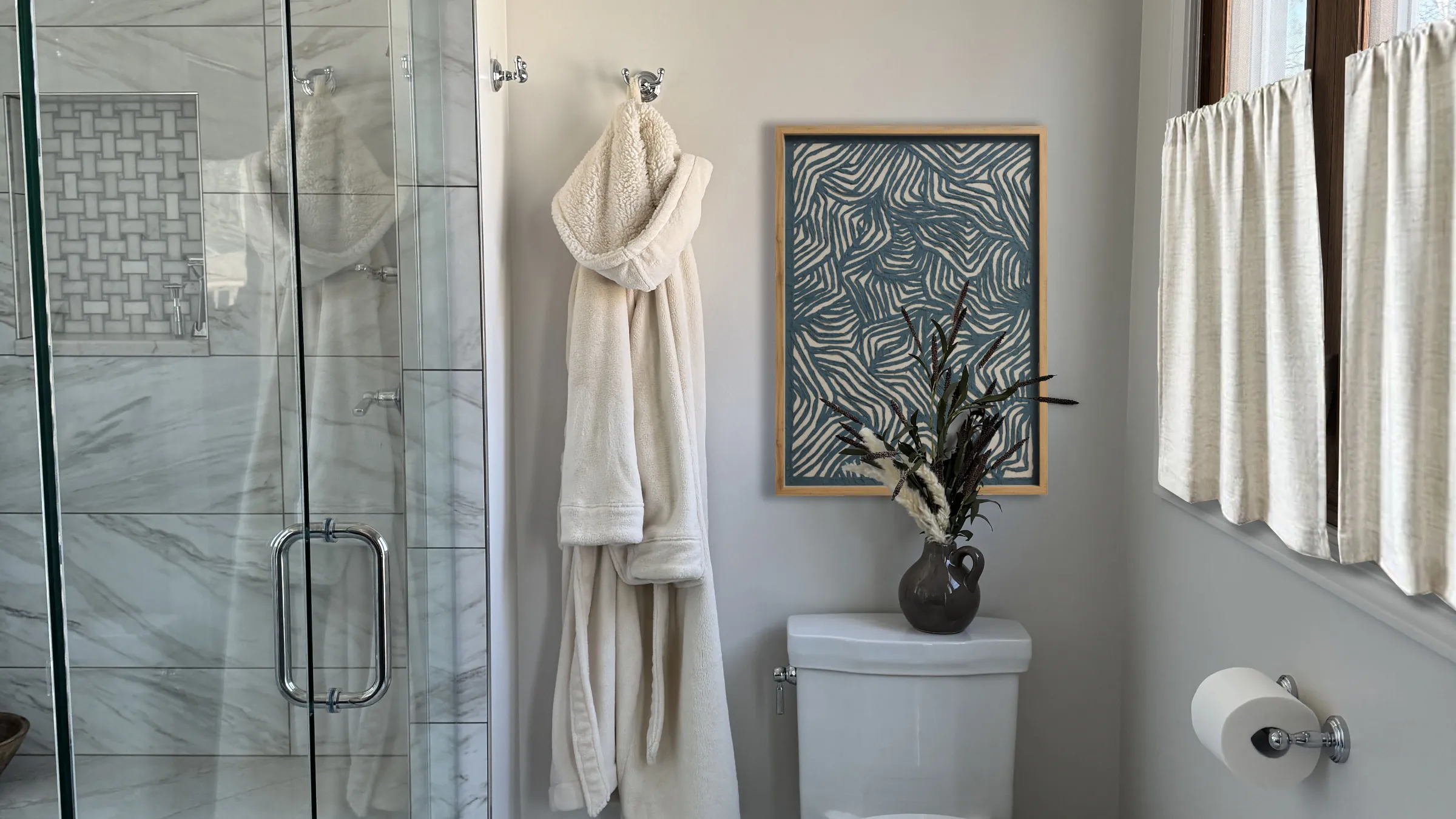 Bathroom remodel featuring a glass shower, robe, framed art, and toilet with decorative vase in Arlington Heights.