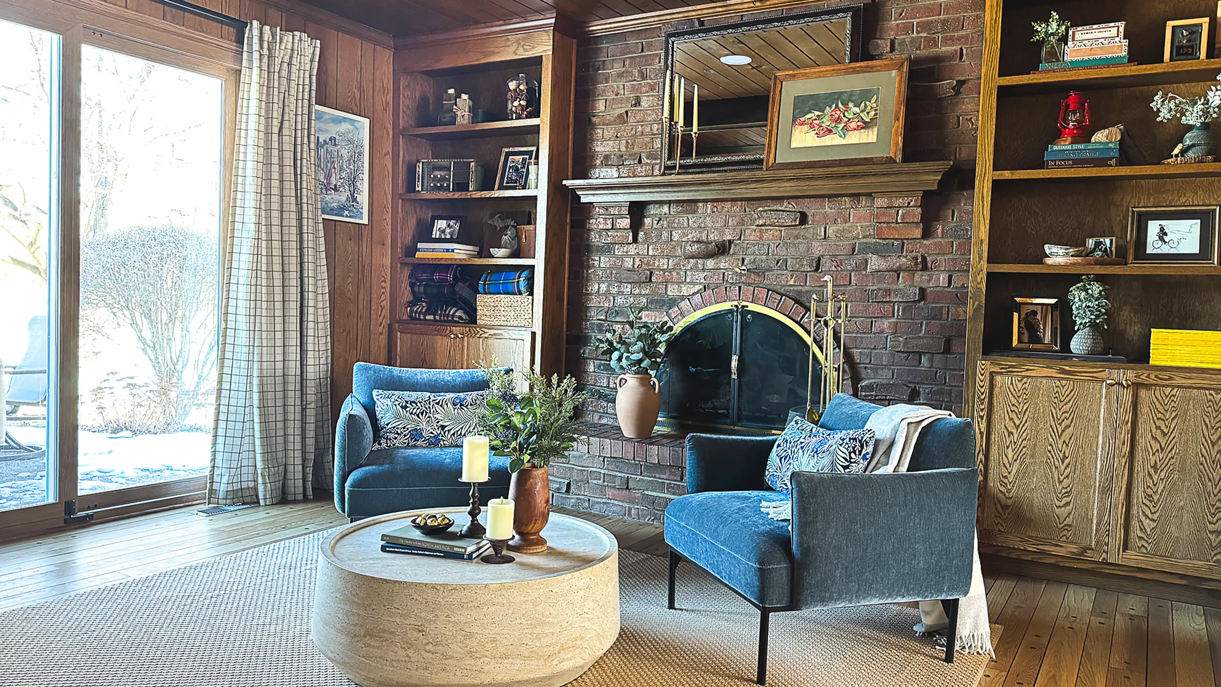 Arlington Heights living room with brick fireplace, custom built-ins, blue chairs, and round travertine coffee table.