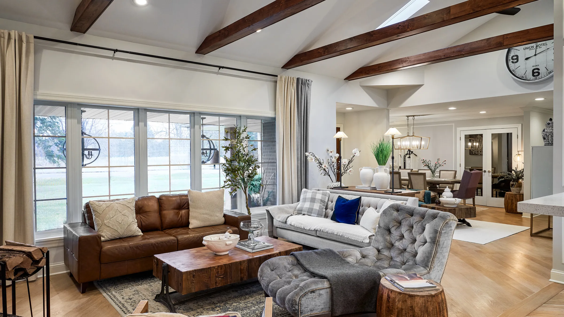Bright living room with wood beams, herringbone floors, leather sofa, gray sofa, and natural light in Prospect Heights, IL.