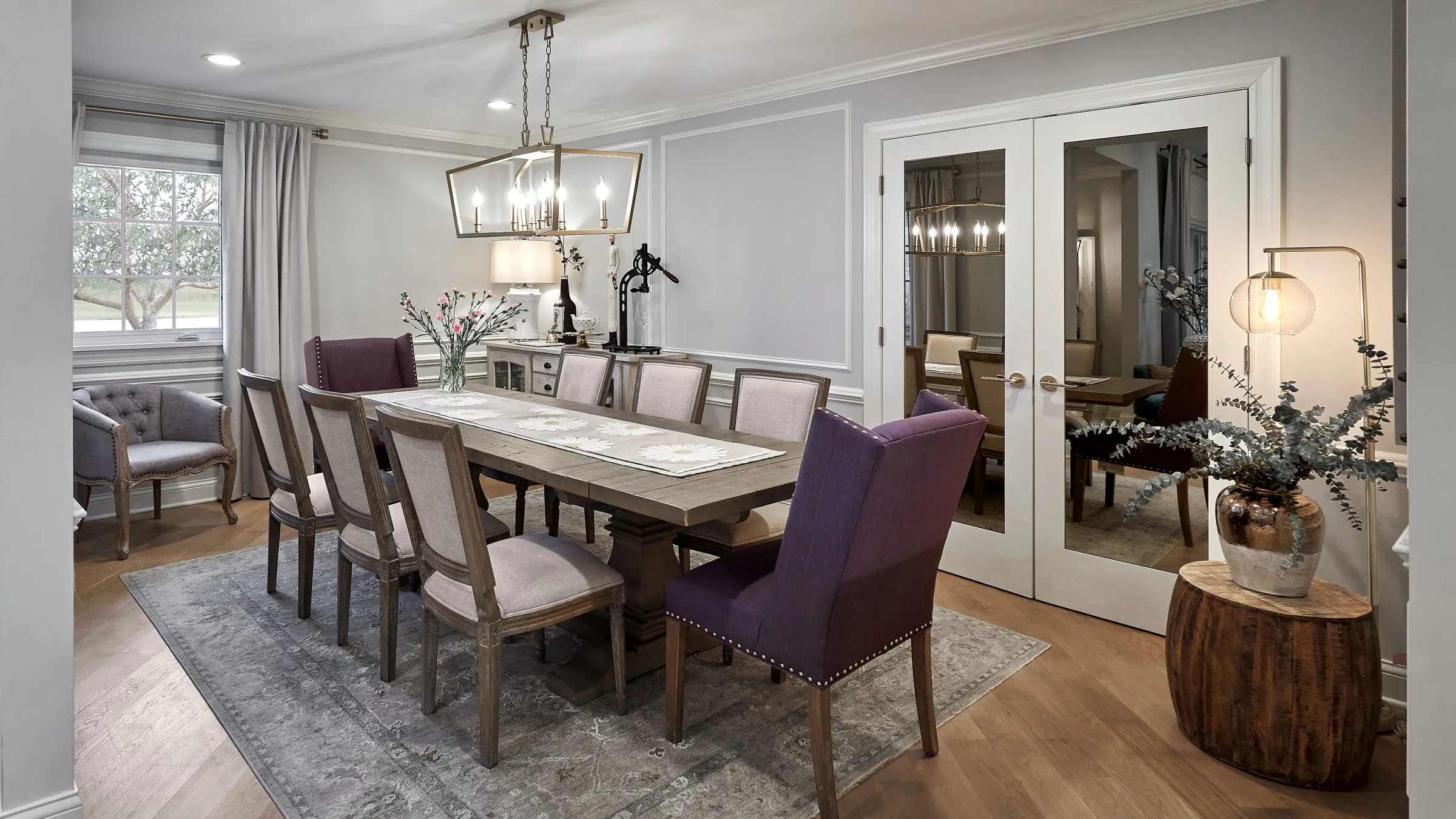 Elegant dining room with wood table, upholstered chairs, modern chandelier, and herringbone wood floors.
