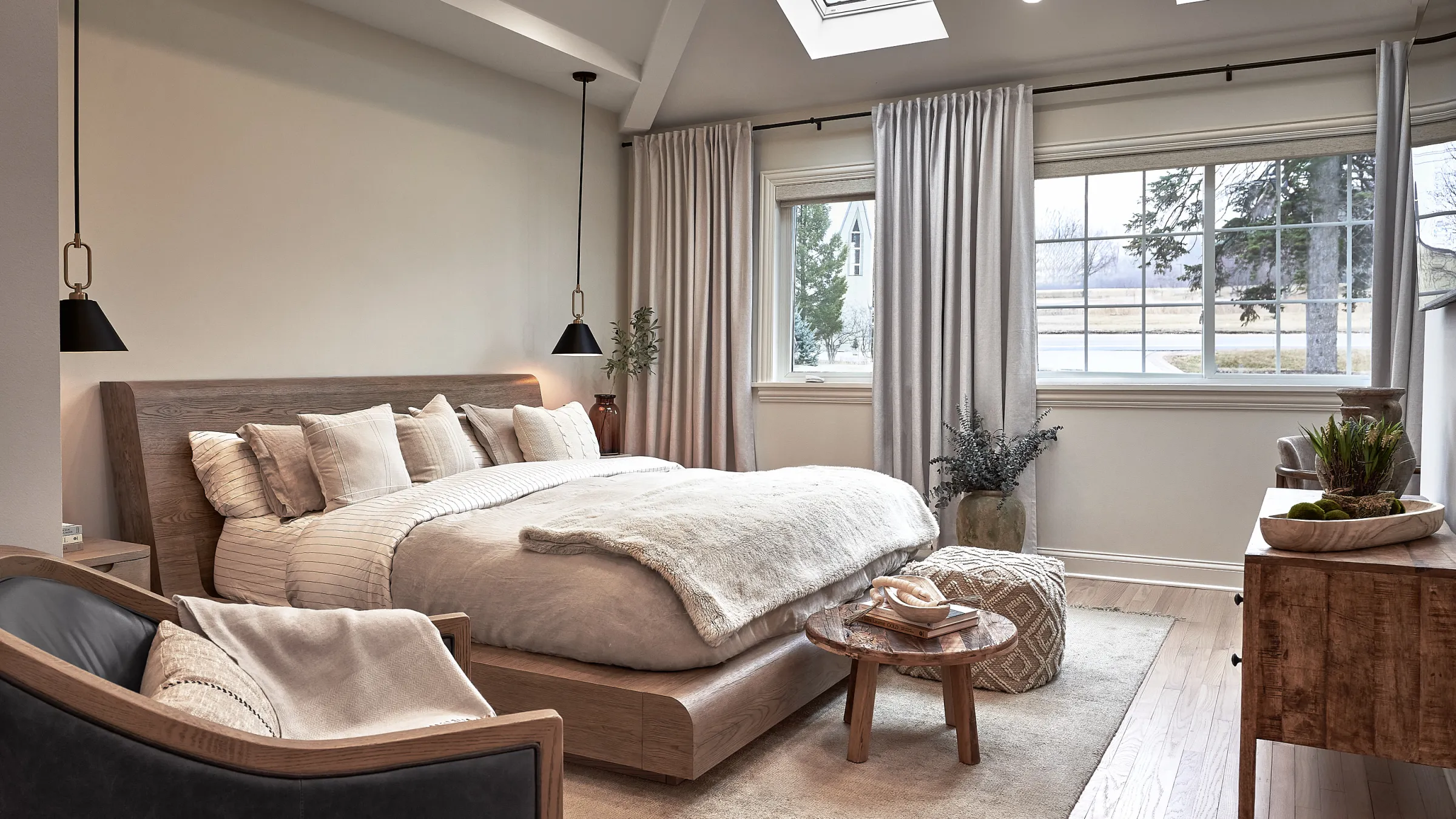Prospect Heights bedroom remodel with wood bed frame, neutral bedding, and large windows. Modern pendant lighting.