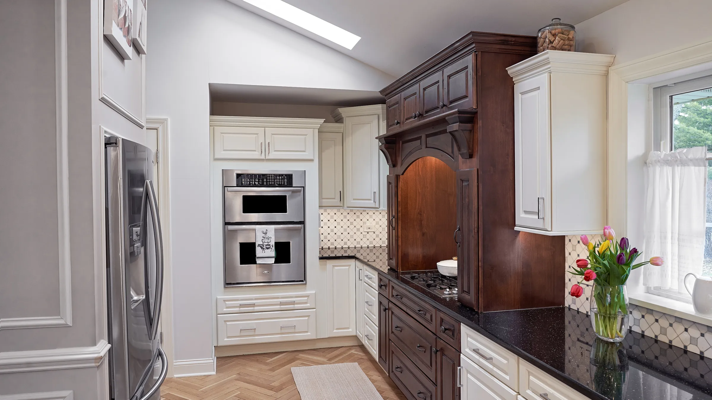 Prospect Heights kitchen remodel featuring custom two-tone cabinetry, herringbone wood floors, and stainless steel appliances