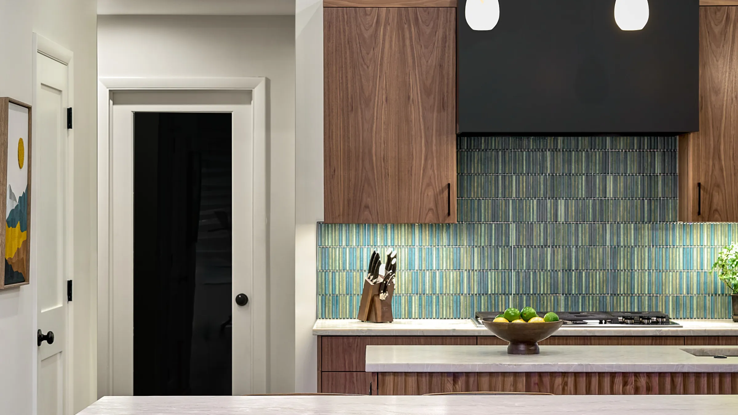 Modern kitchen remodel with walnut cabinets, blue backsplash, white countertops, and stainless steel appliances.