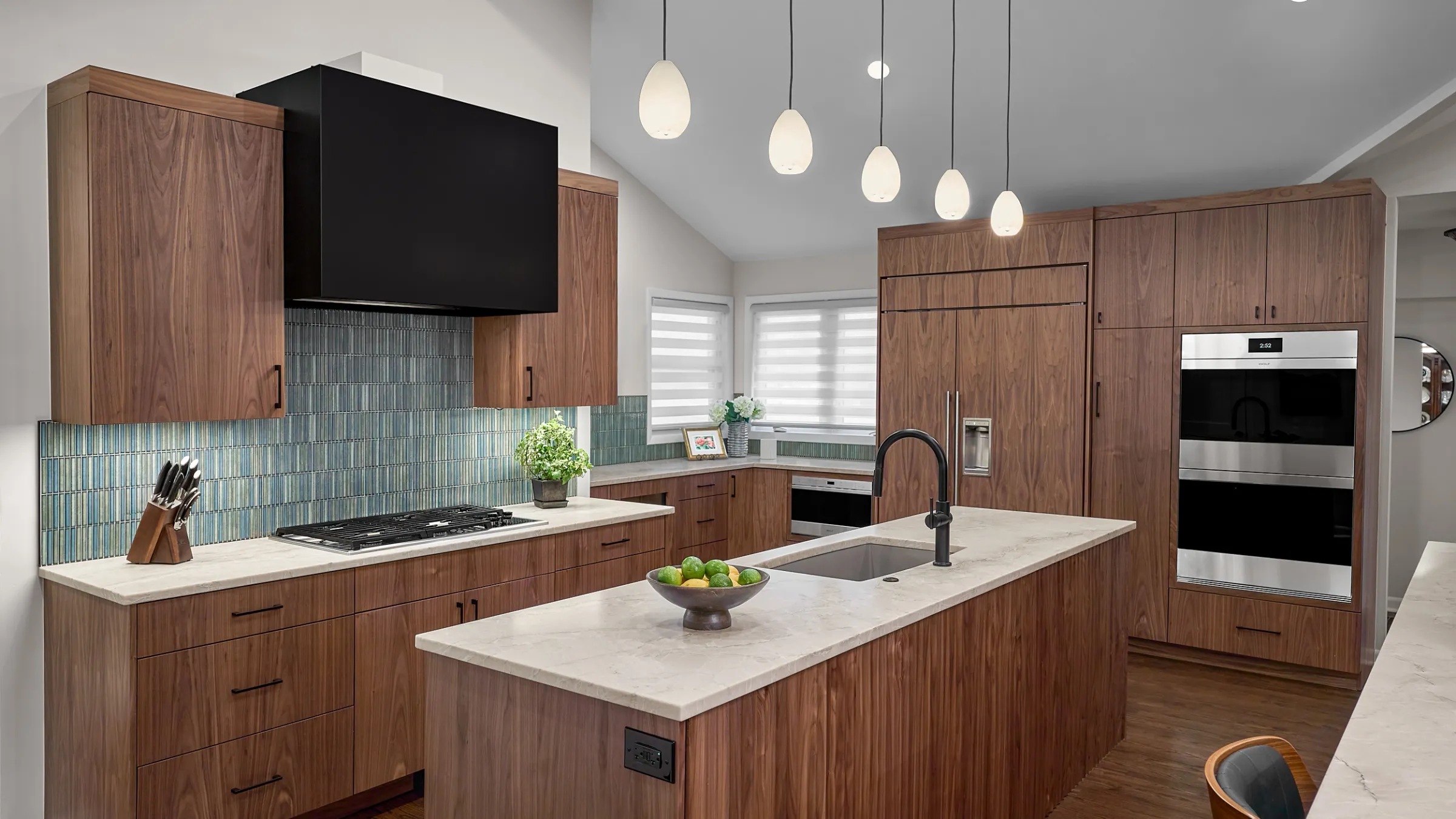 Modern kitchen remodel with wood cabinets, island, marble countertops, stainless steel appliances, and blue tile backsplash.