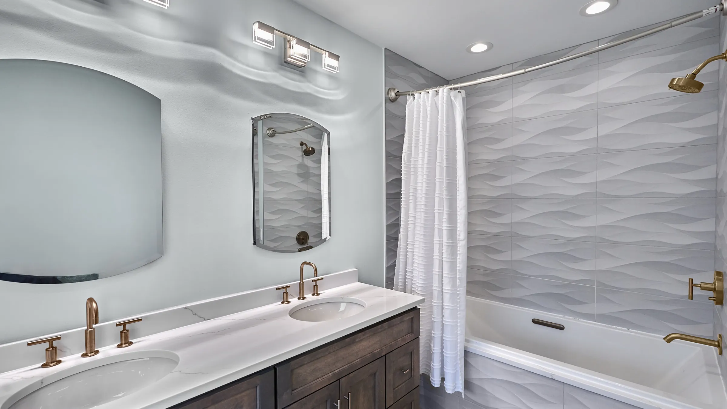 Modern bathroom remodel with gray wave tile, a white quartz countertop, and bronze fixtures in Mount Prospect, IL.