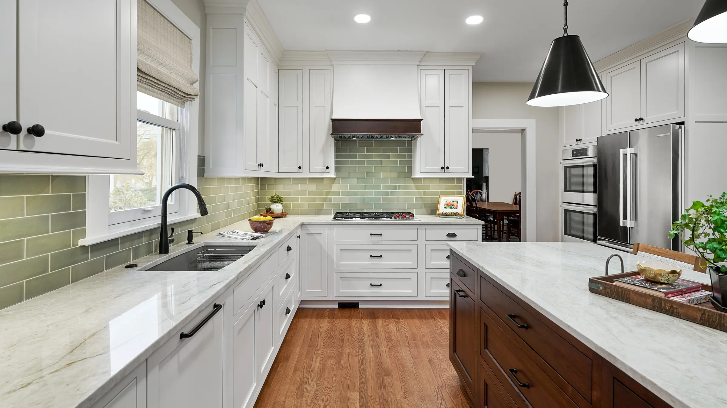 Bright kitchen remodel featuring white cabinets, marble countertops, hardwood floors, and green subway tile backsplash.