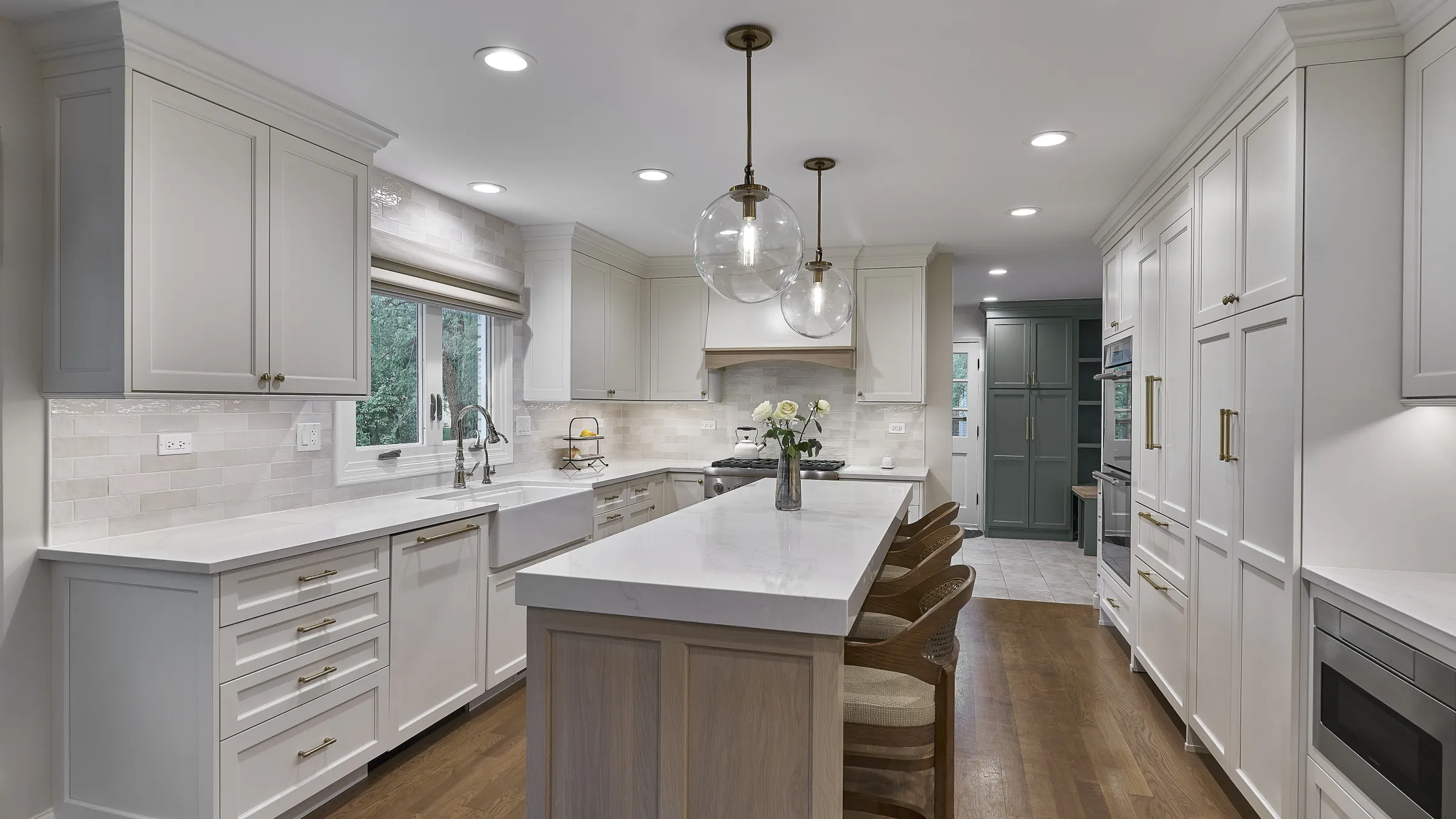 Bright white kitchen with shaker cabinets, quartz countertops, subway tile backsplash, farmhouse sink, wood island, and penda
